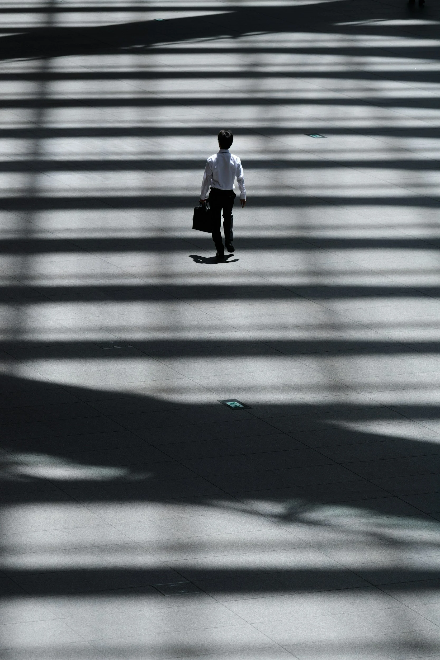 Business professional walking alone through a large corporate space, representing independent decision-making, leadership and navigating complex business environments.