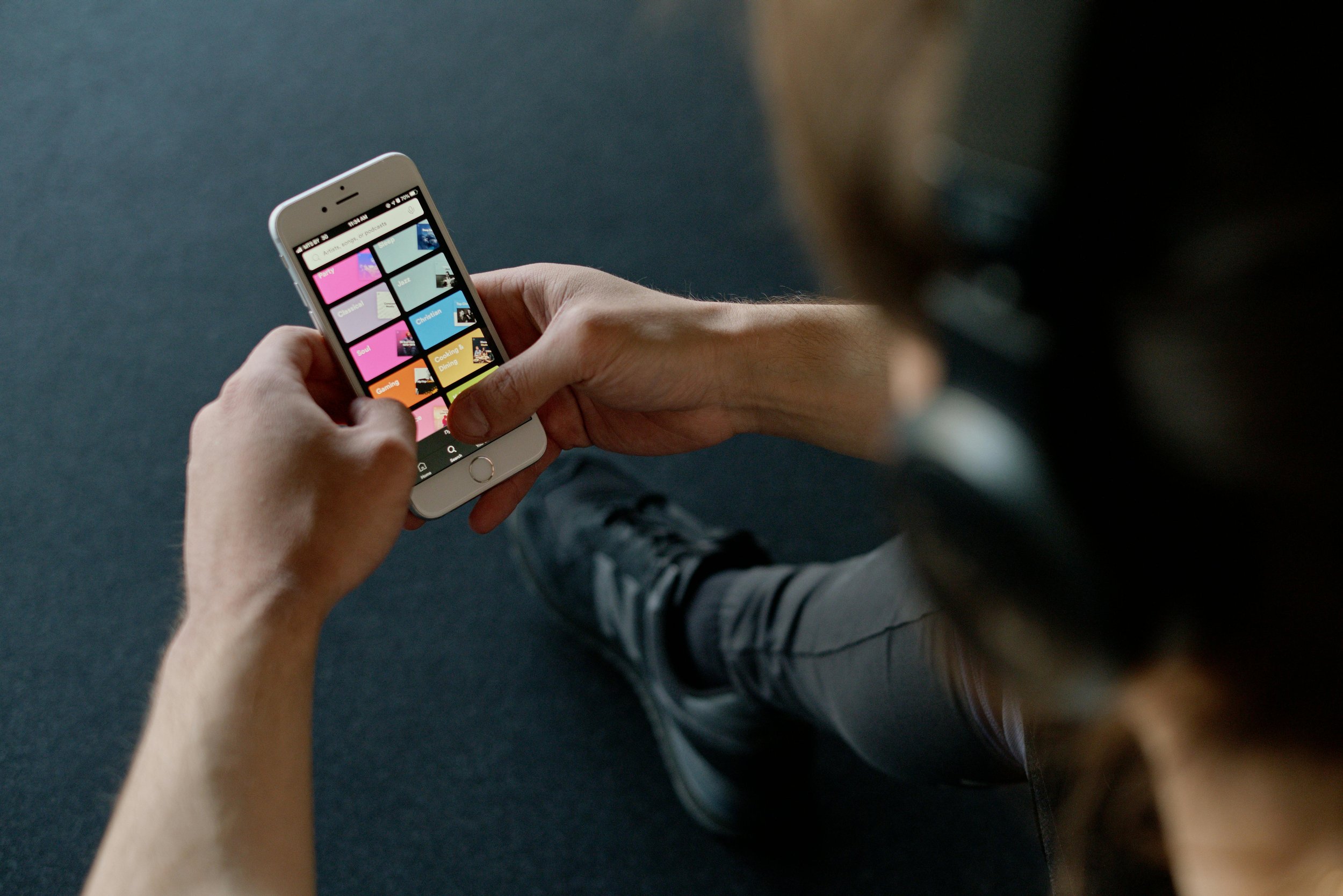 Person in athletic wear browsing a colorful fitness app on a smartphone representing accessible online coaching and workout program delivery. Photo by Ivan Samkov on Pexels