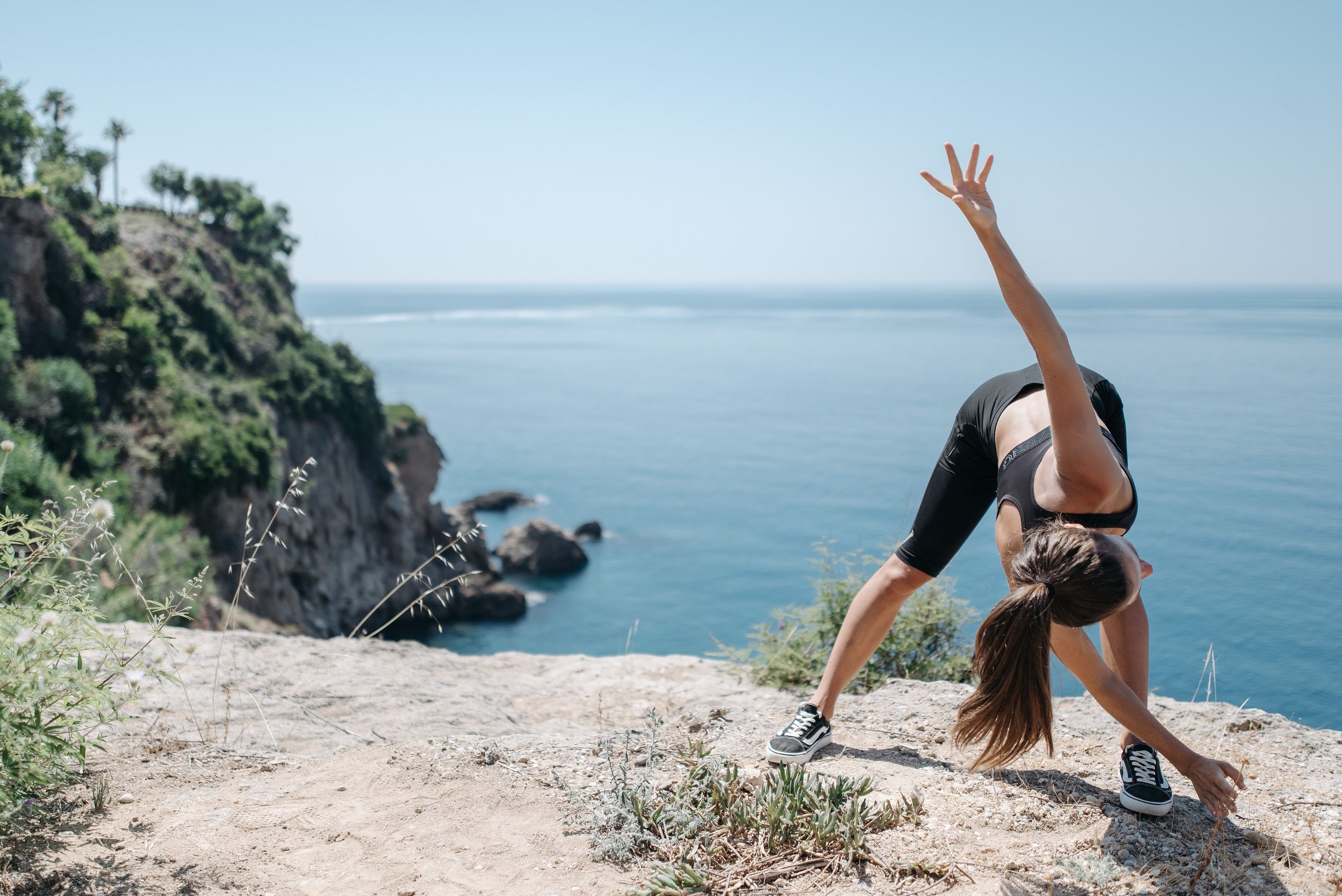 Woman performing a deep lateral stretch on a coastal cliff overlooking the ocean as part of an outdoor flexibility and mobility fitness routine. Photo by Pavel Danilyuk on Pexels
