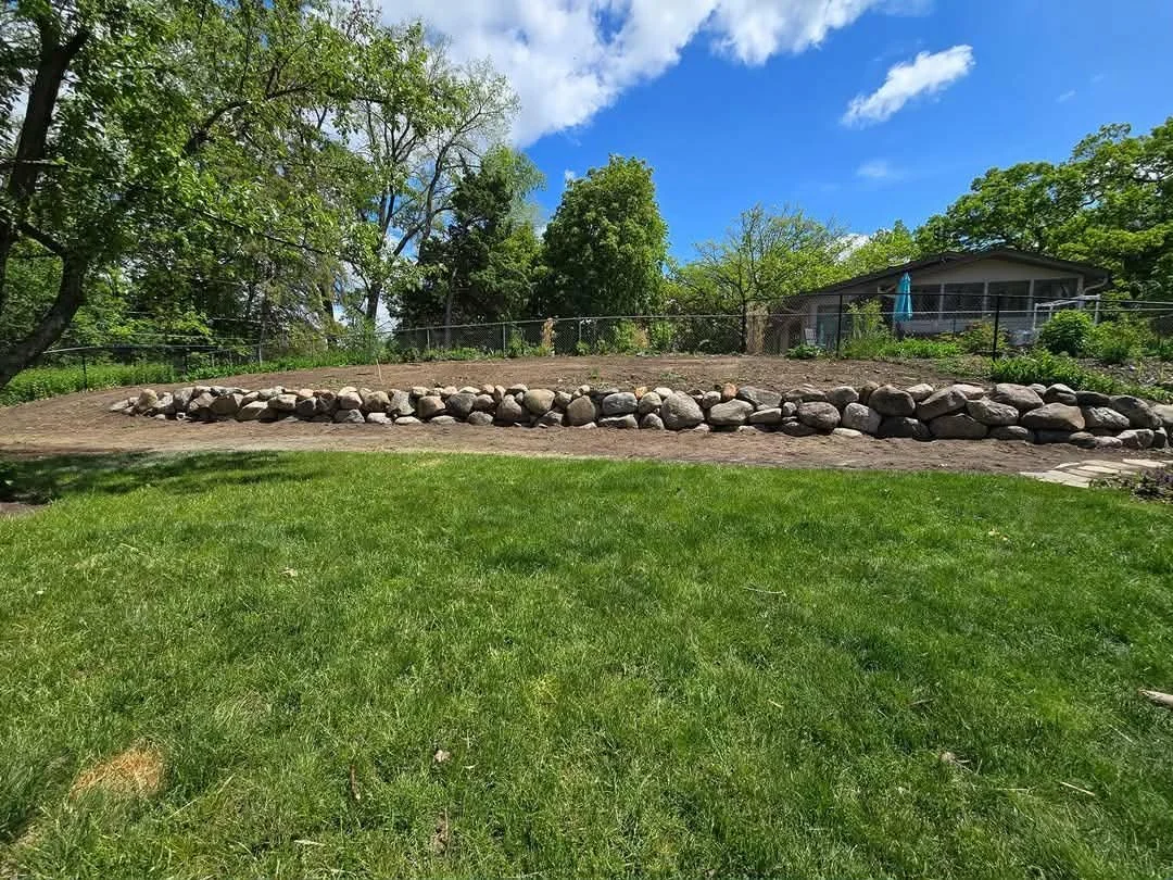 curved boulder retaining wall supporting backyard slope