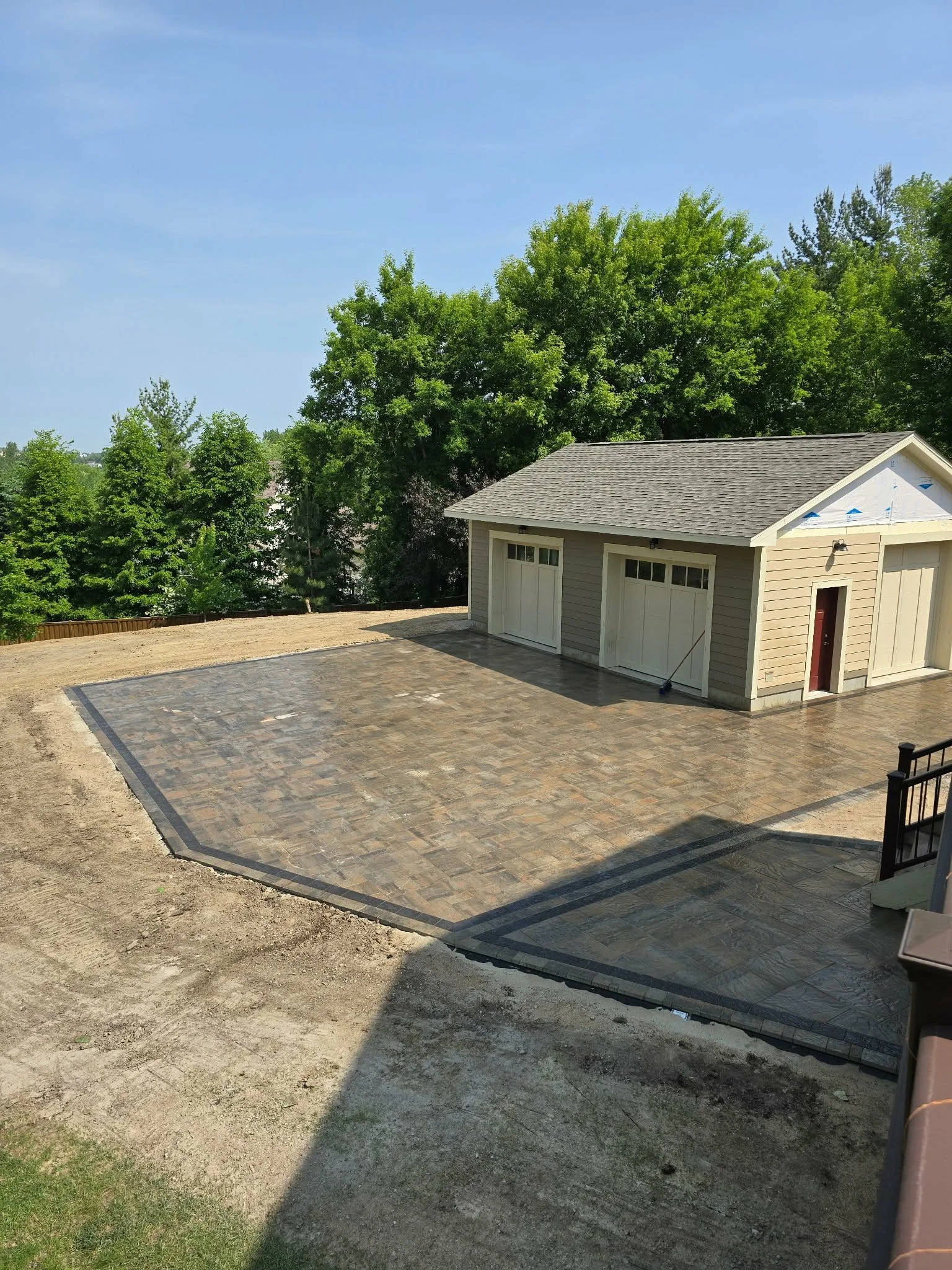 large paver patio installation around detached garage outdoor space