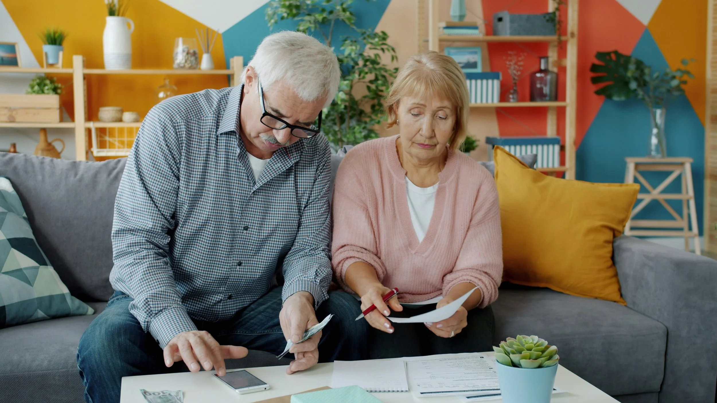 An older couple sitting at a kitchen table reviewing financial documents together
