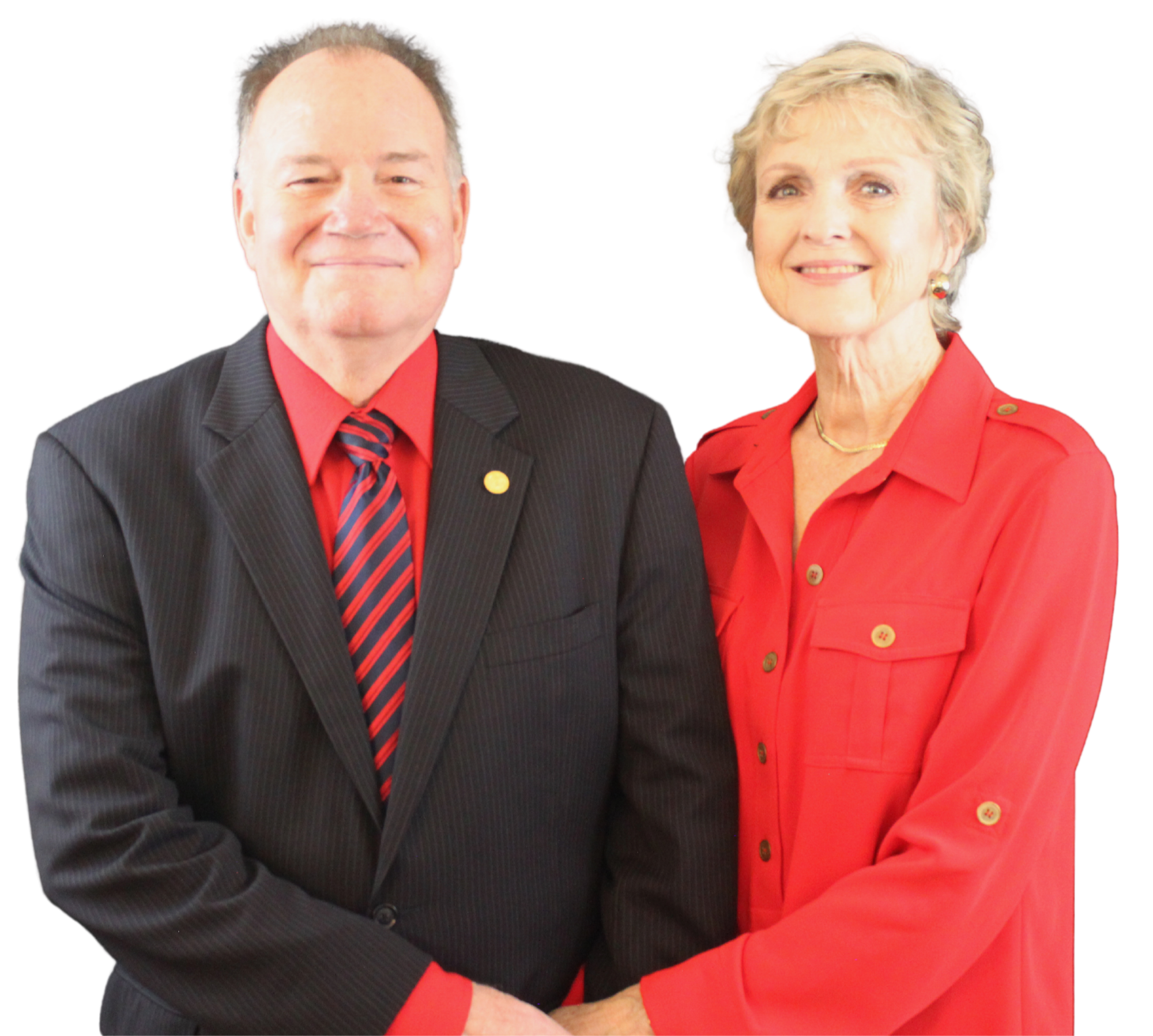 A man and a woman standing together, both dressed in formal attire with red accents. The man is wearing a dark suit with a red shirt and a striped tie, while the woman is wearing a red blouse with gold buttons. They are smiling and holding hands.