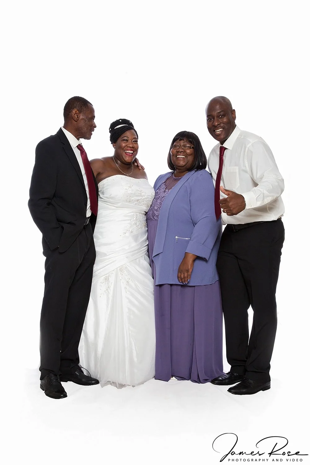Four people standing together, smiling, dressed in formal attire, with a woman in a white wedding gown.