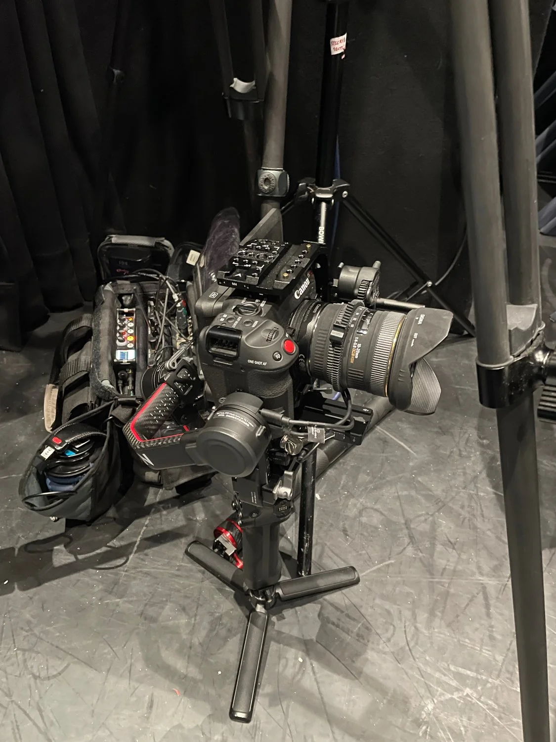 A professional camera mounted on a stabilizer rig with various accessories, surrounded by equipment and tripods.