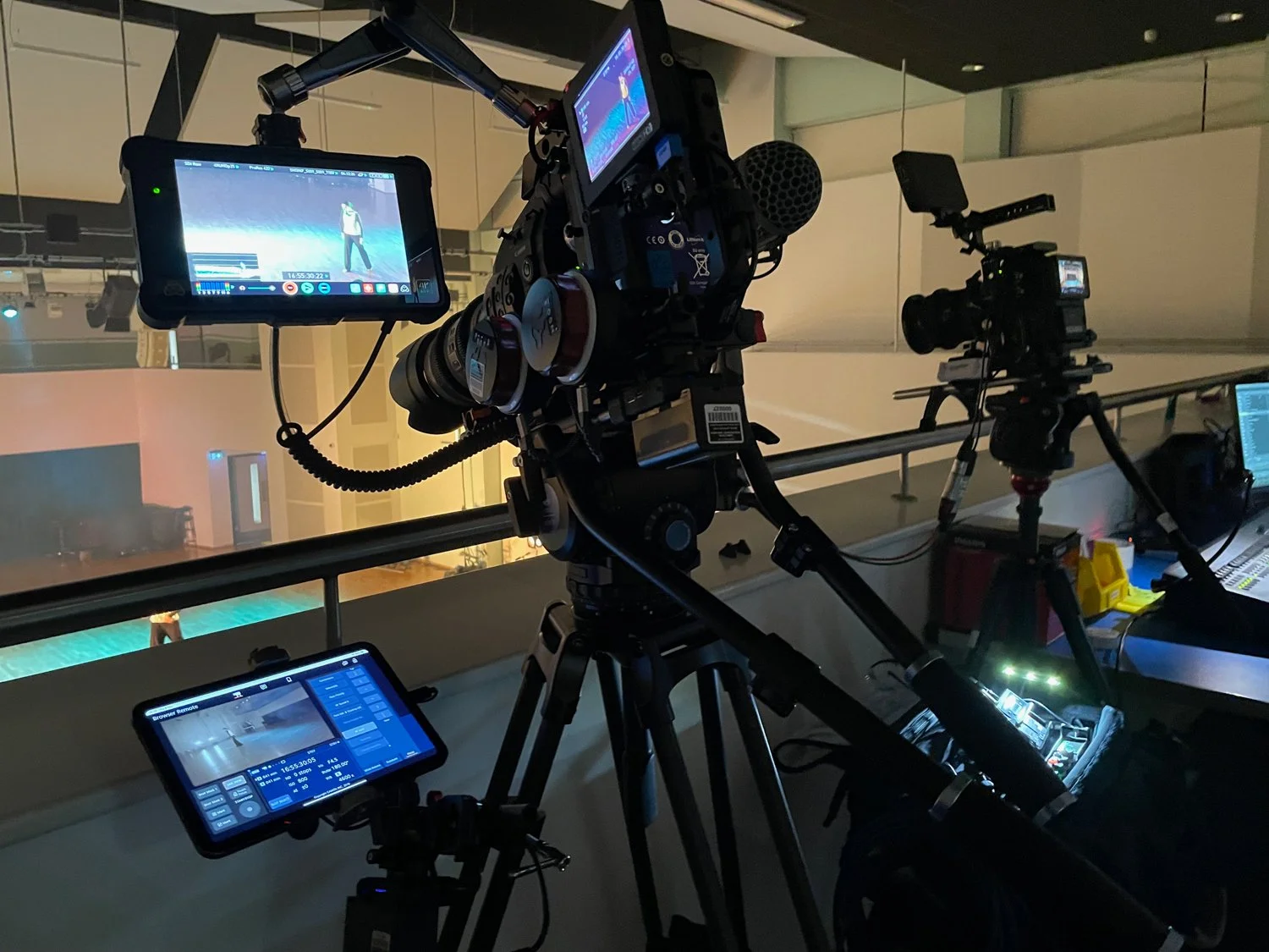 Cameras and camera equipment set up in an indoor studio or event space, with screens displaying the recording footage.