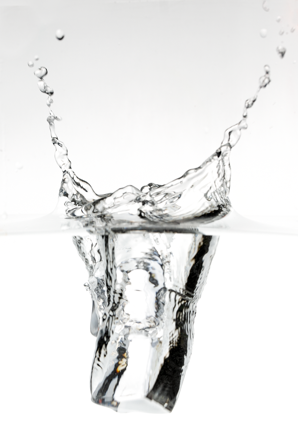 A clear ice cube splashing into water, creating a splash and water droplets.