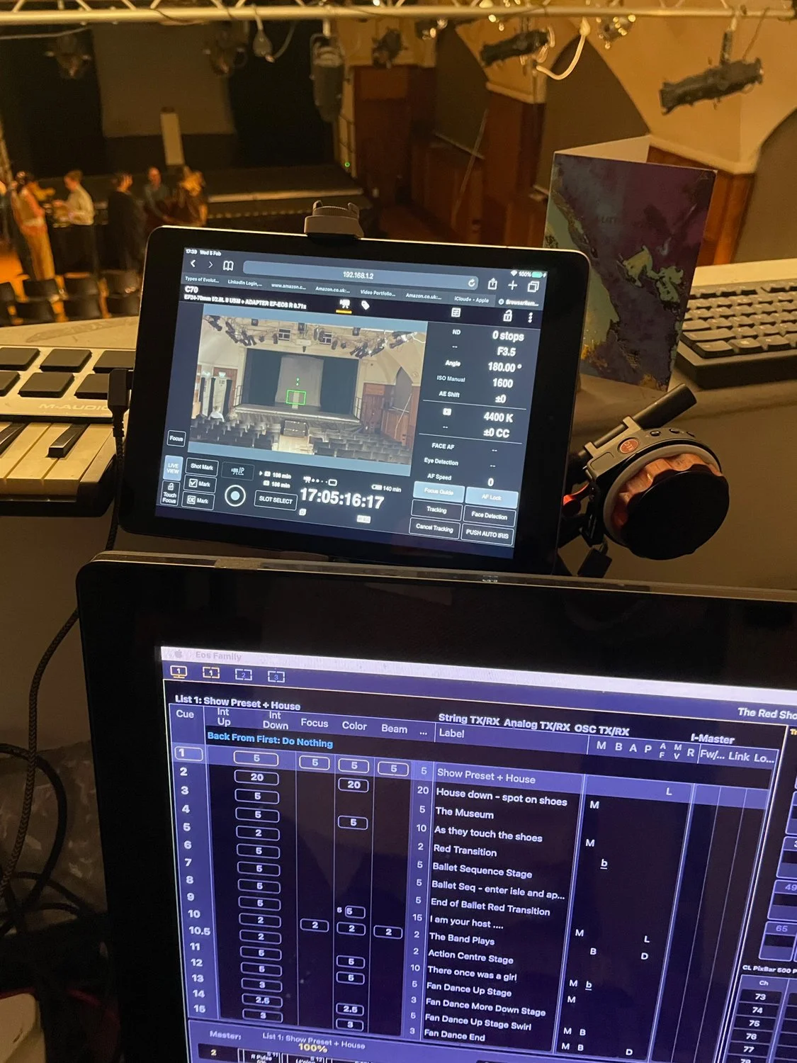 View of theater stage and audience from behind the scenes with lighting and technical equipment.