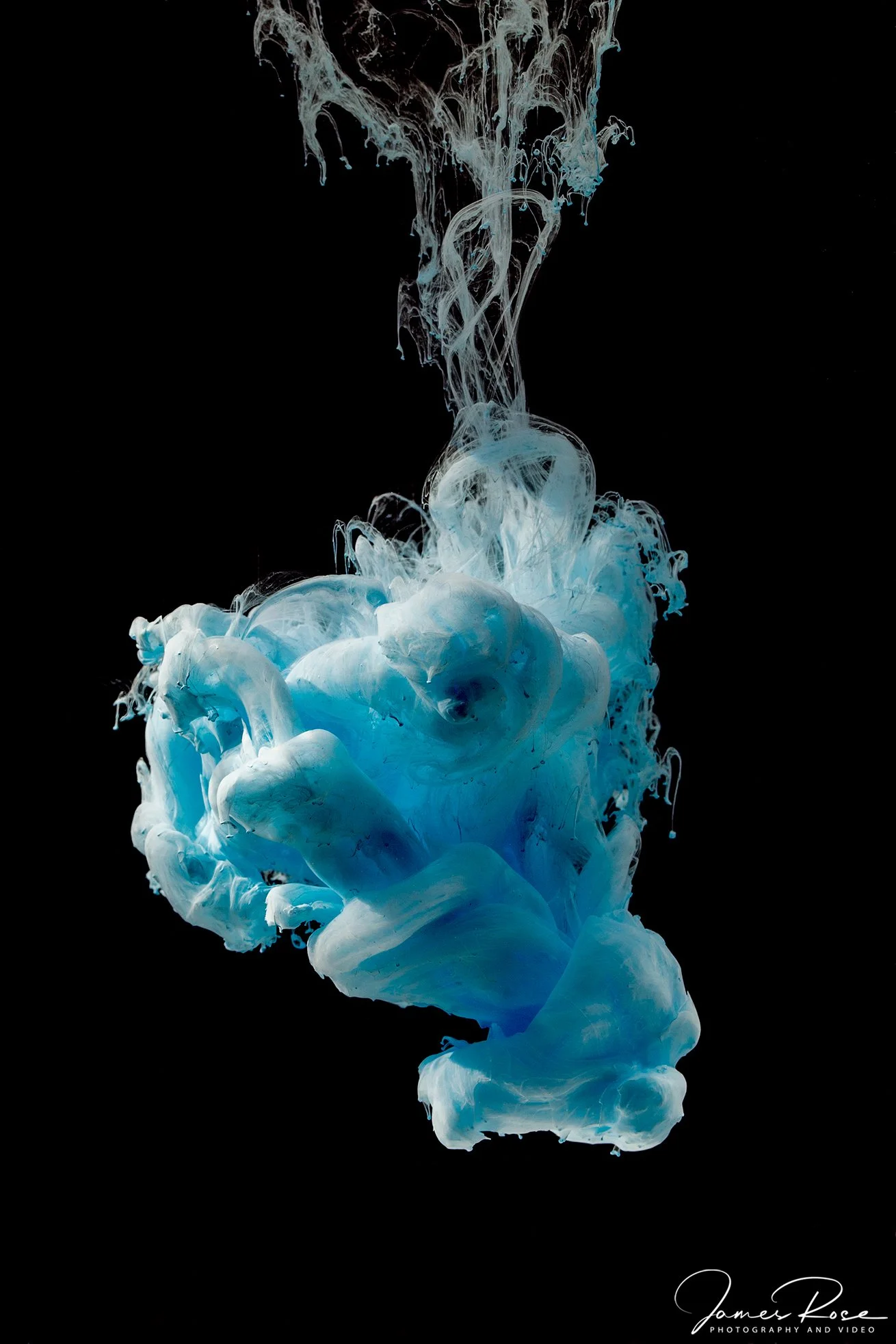 Blue and white ink swirling in black water background.