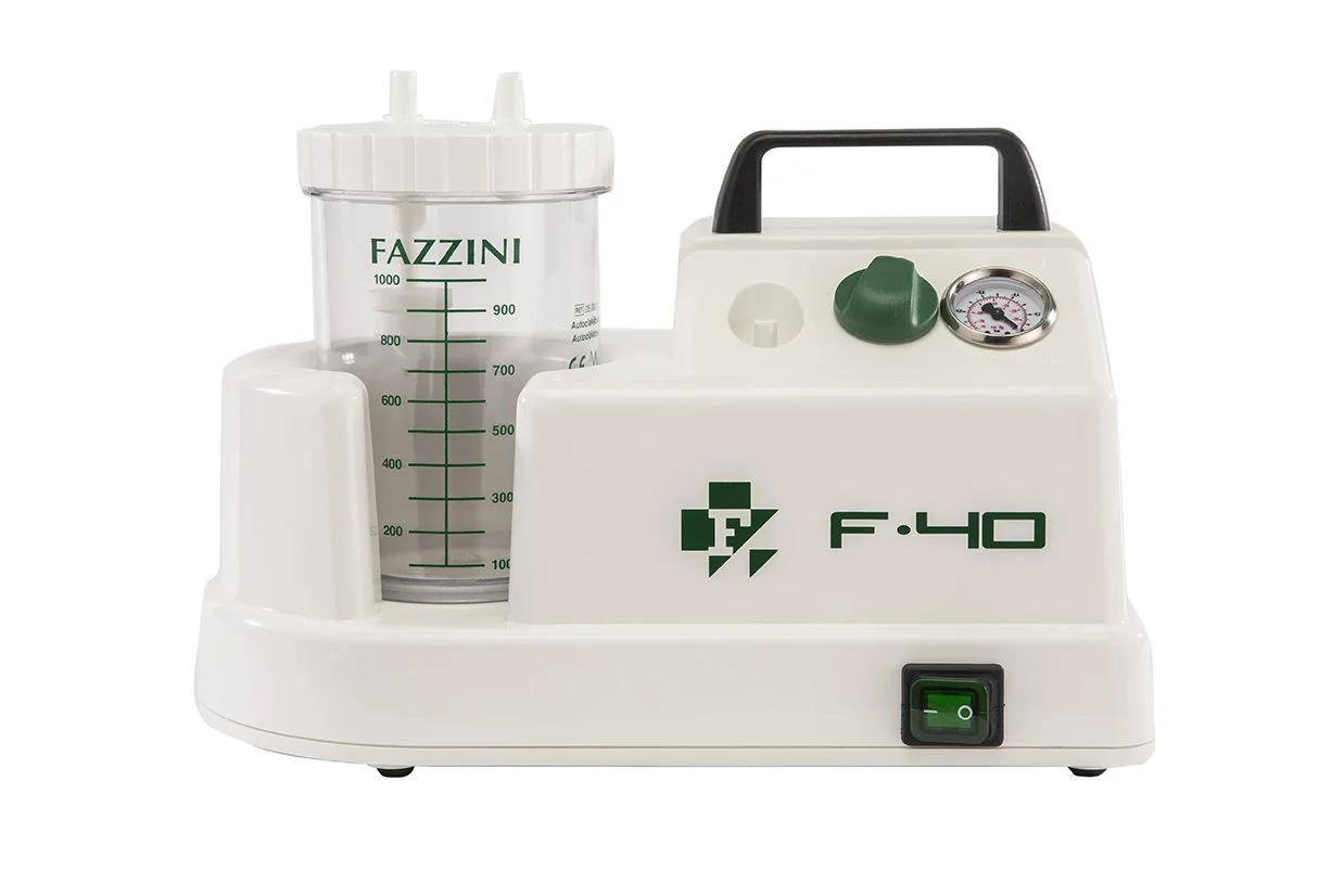 A medical aspirator device with a white body, a hand-operated vacuum gauge, a green power switch, and a transparent container with measurement markings.
