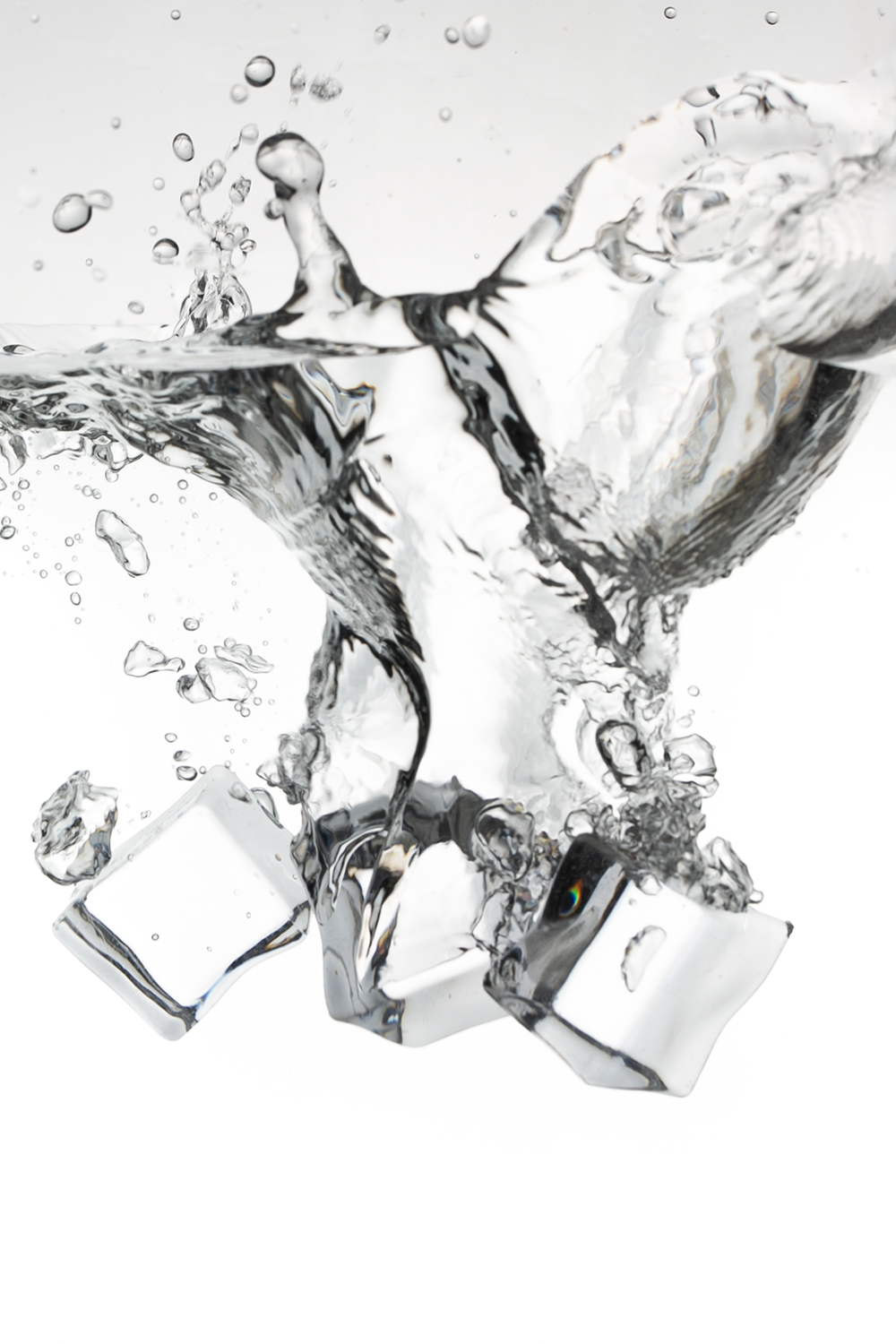 Ice cubes splashing into water with bubbles and ripples