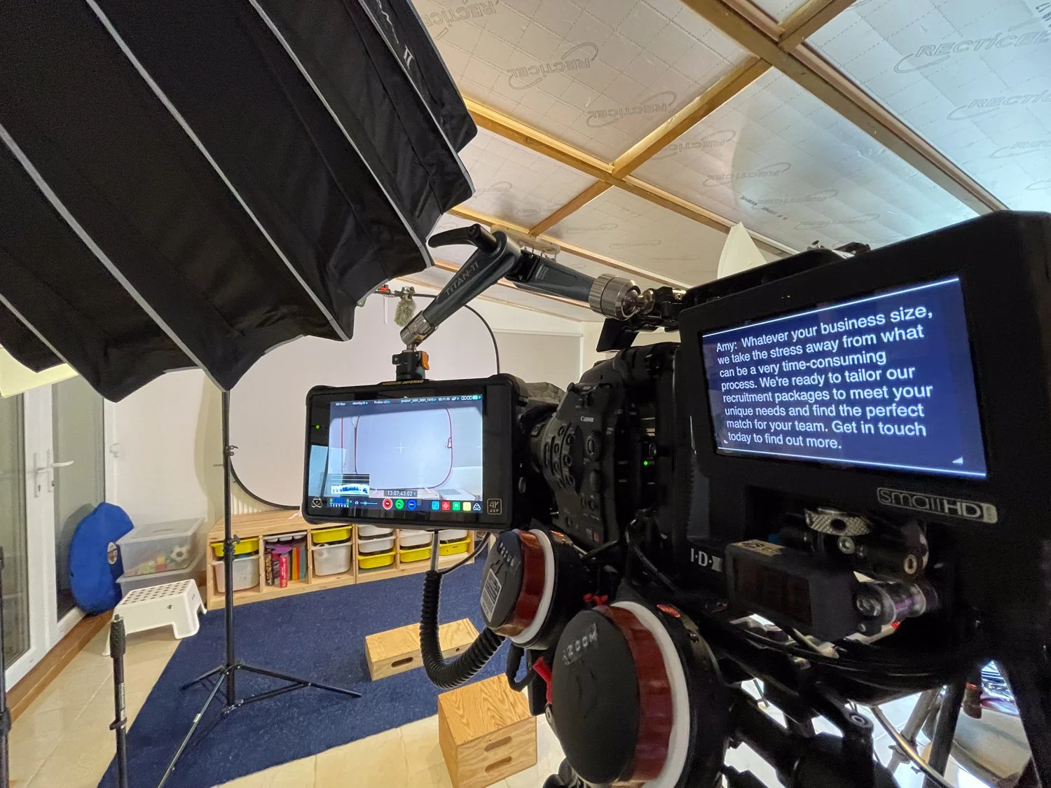 Video recording studio with professional camera, monitor, and lighting setup in a room with storage drawers.