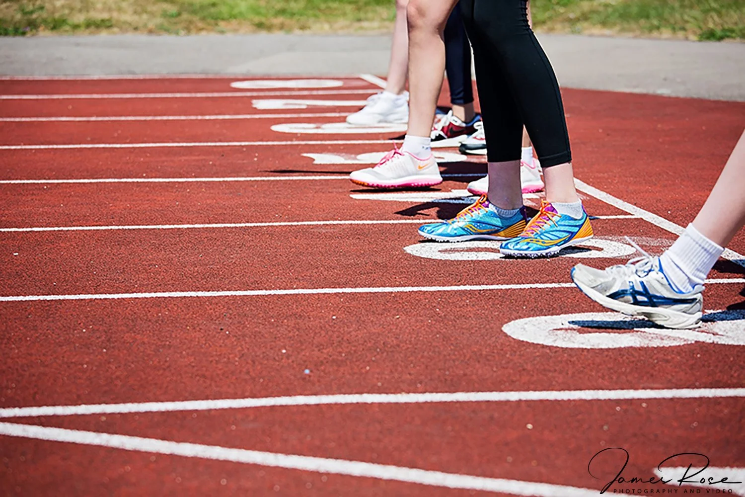 Start line of a running track with runners in athletic shoes ready to begin a race.