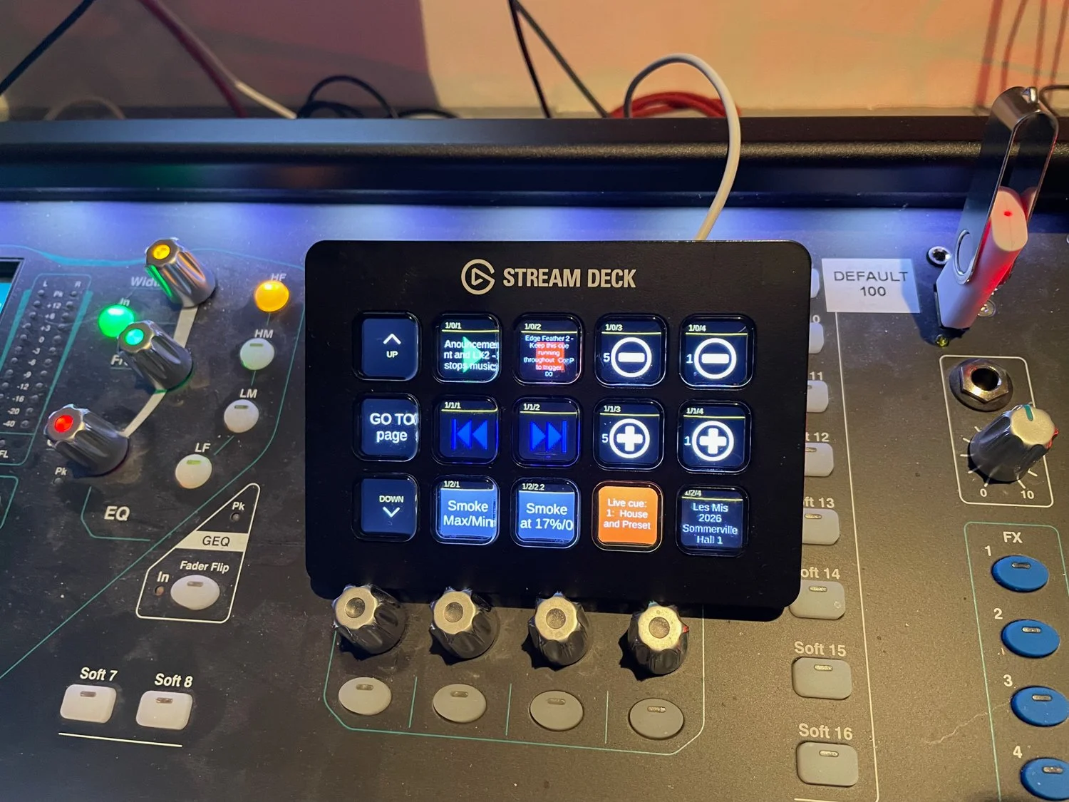 A digital audio mixing console with various knobs, sliders, and a small touchscreen control panel labeled 'Stream Deck' in the center. The console has colorful controls including green, red, yellow, and gray knobs and buttons, some labeled with funct