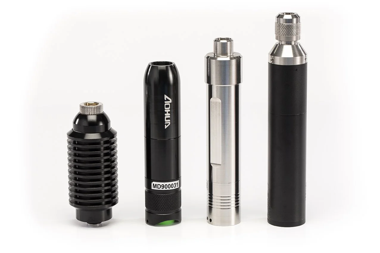 Four handheld tattoo machine grips in a row, varying in size and design, with black and metallic finishes.