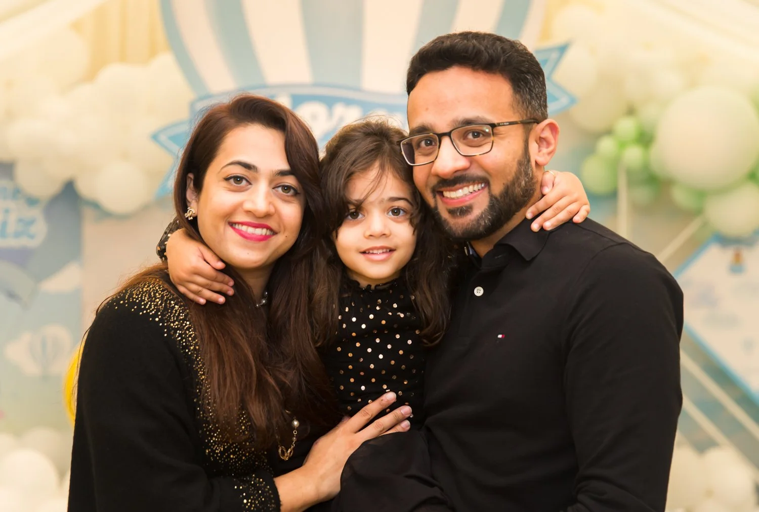 Happy family of three smiling and hugging at a celebration event.
