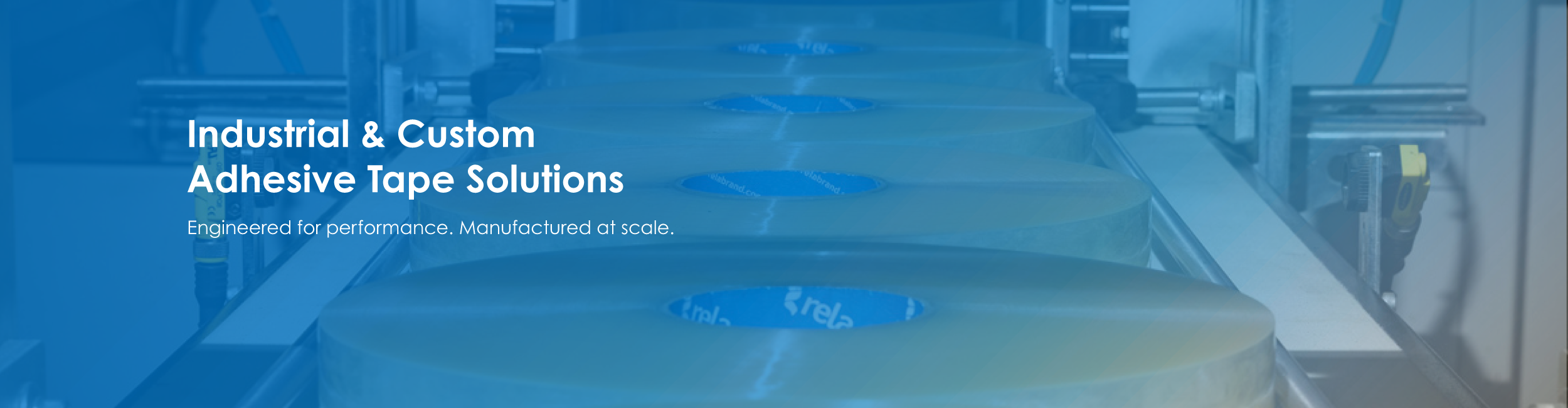 Industrial rolls of adhesive tape on a manufacturing line.