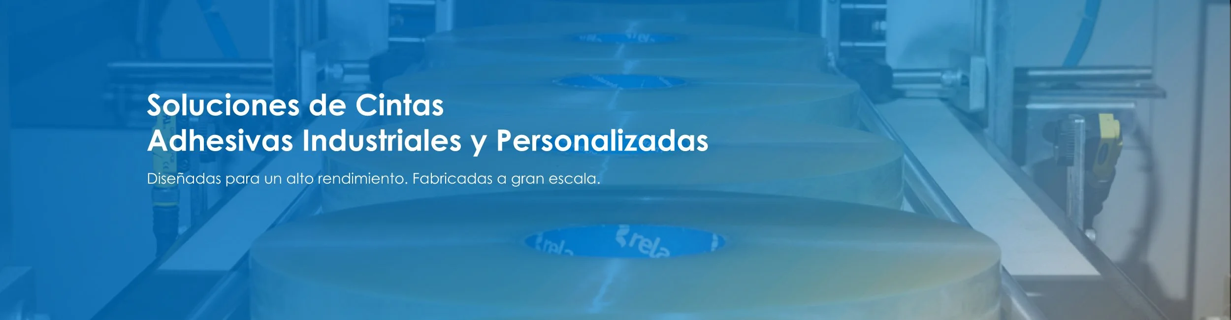 Industrial rolls of adhesive tape on a manufacturing line.