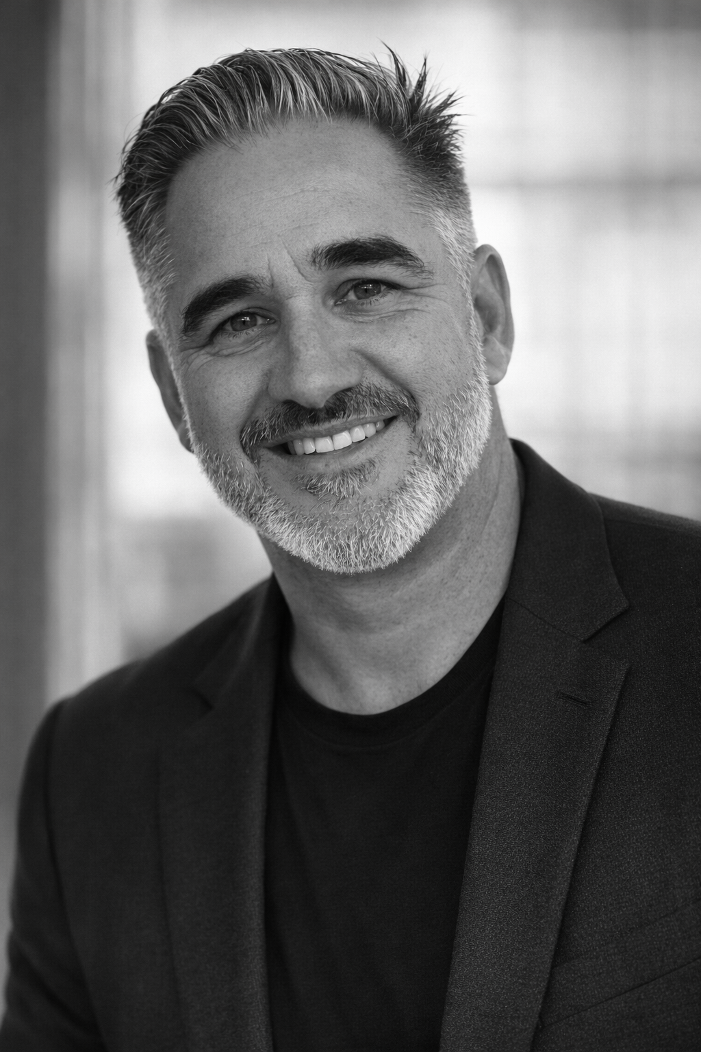 Black and white portrait of Samuel Carter wearing a dark blazer and T-shirt, indoors.