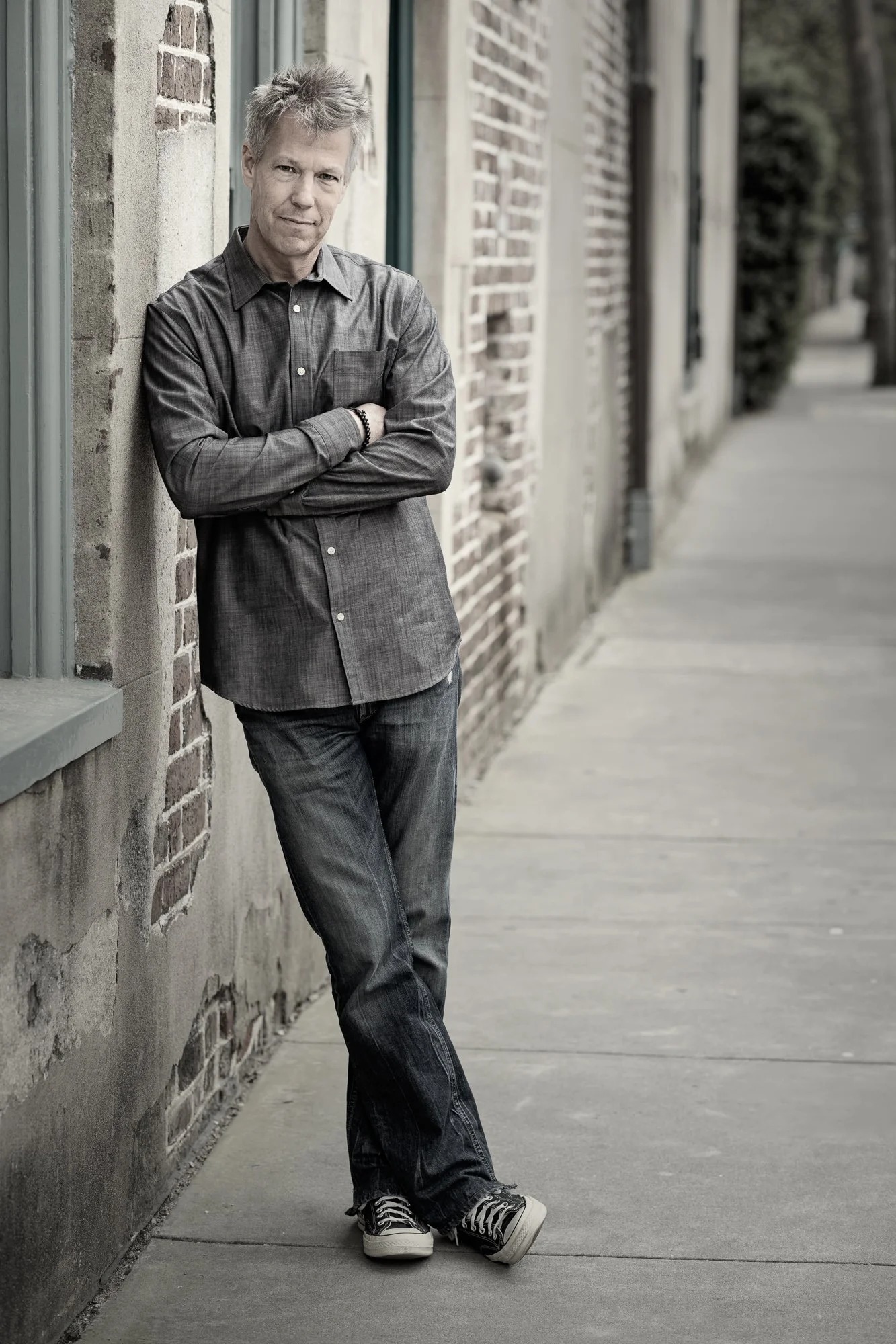 Kevin Holliday leaning against a brick and stucco wall in historic downtown Charleston South Carolina.
