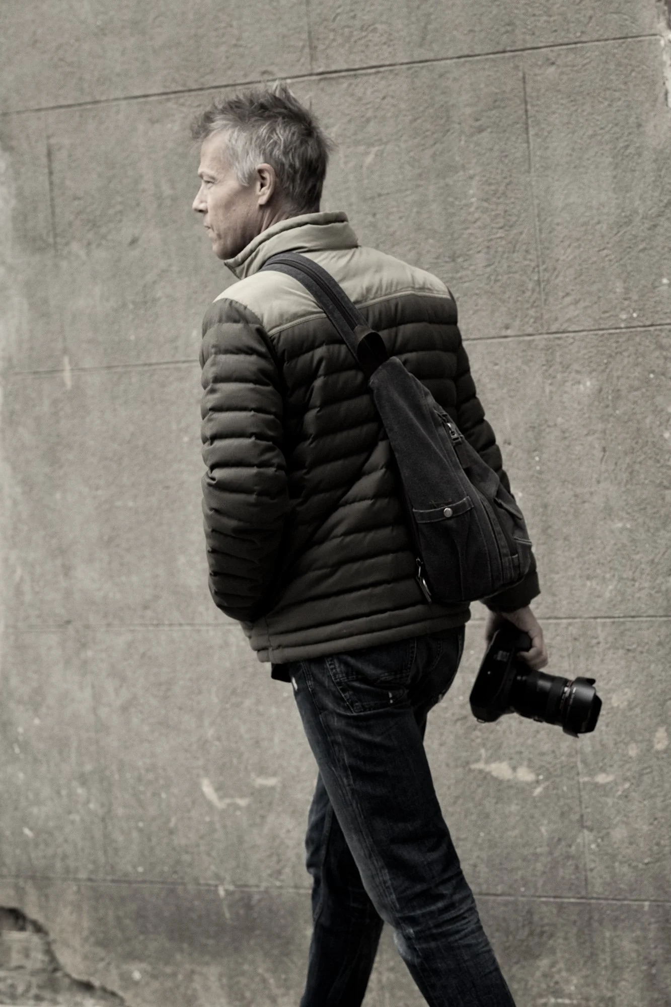 Kevin Holliday walking with his camera by a brick and stucco wall in historic downtown Charleston, South Carolina.