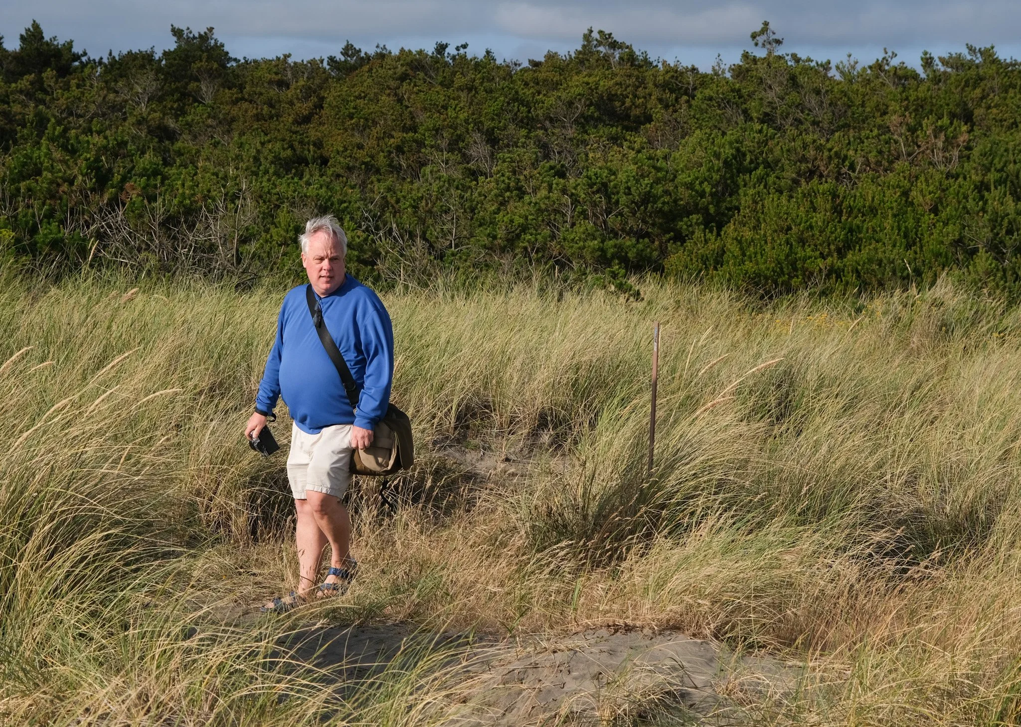Man walking through grass with camera