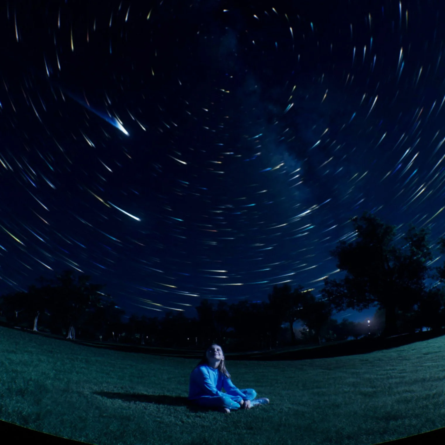 Person sitting under star-filled night sky