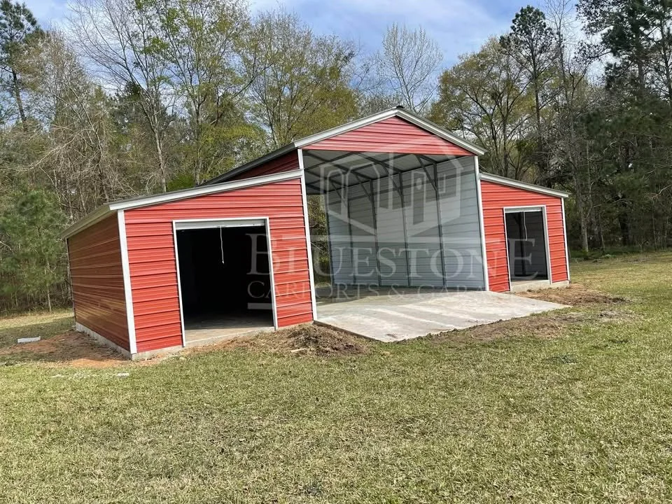 A red metal barn with two large doors and a screened-in upper level, situated on a grassy area with trees in the background.