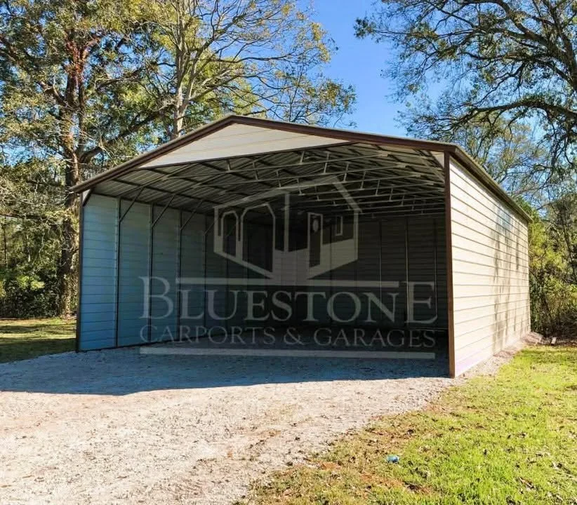 Empty metal storage garage with open front, surrounded by trees and grass.