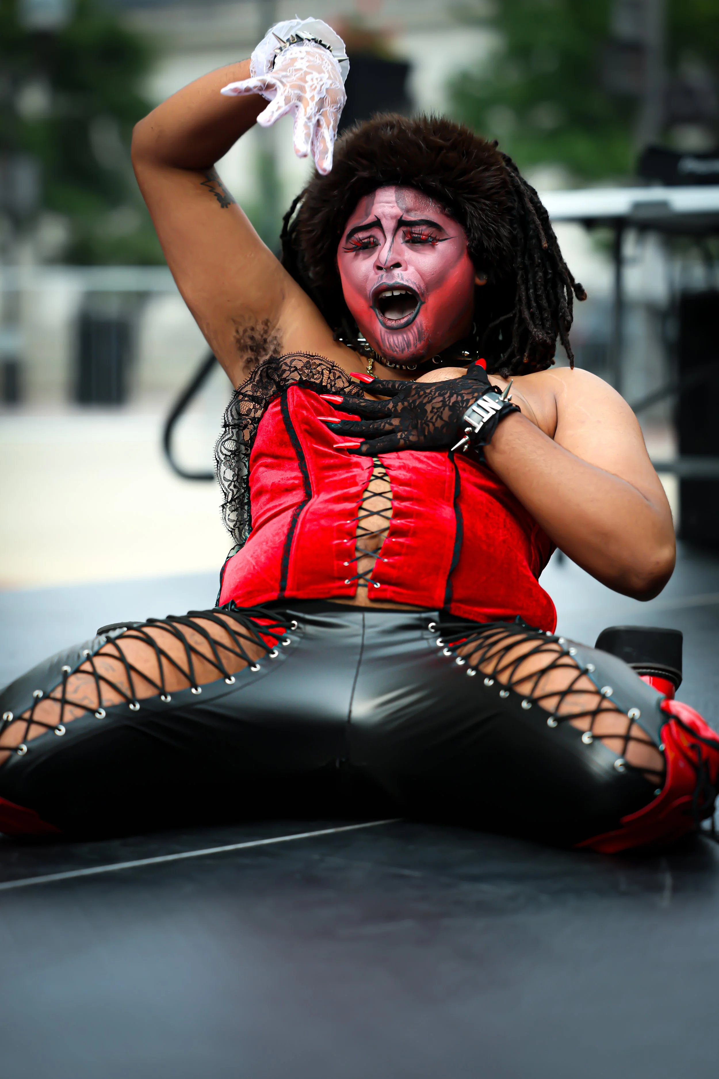 Performer with dramatic makeup and in a radical costume performing passionately on stage.