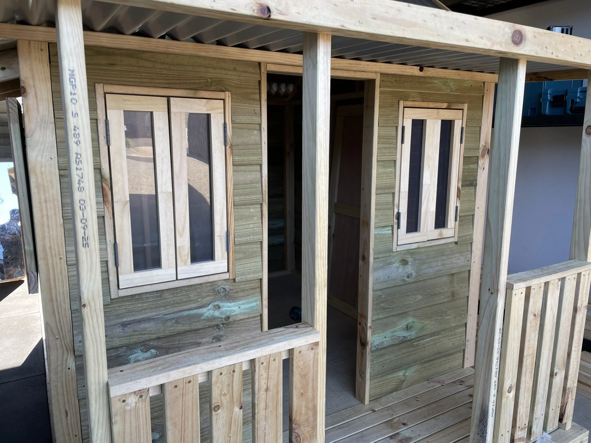 Unfinished wooden structure, possibly part of a deck or small building, with windows and framing in progress.