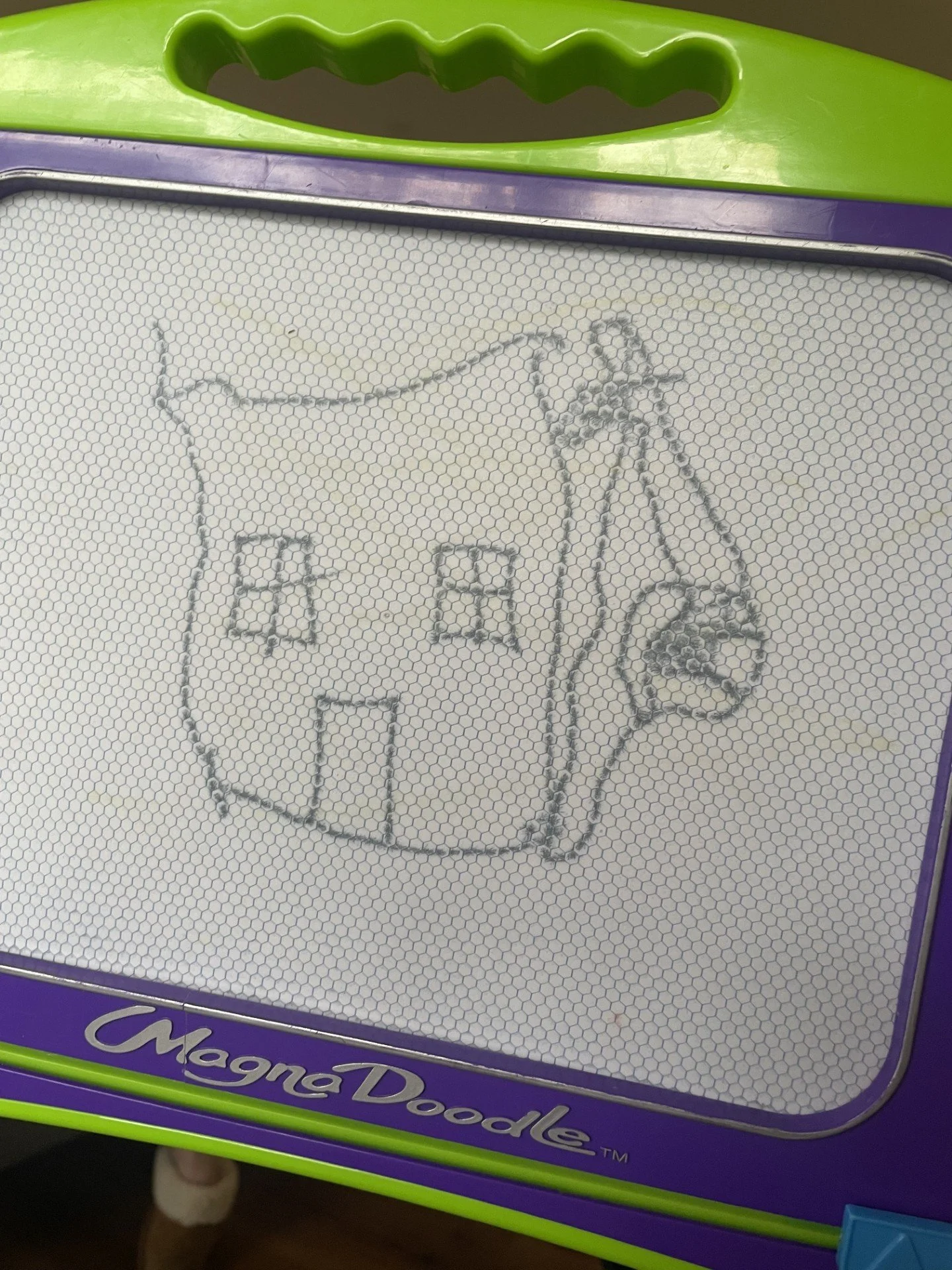 The image shows a magnetic drawing board with a drawing of a cubby house. Drawn by a toddler who loves cubby houses.