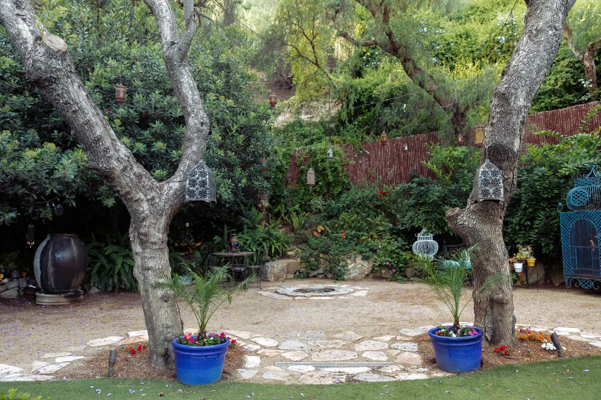 Secluded hillside garden at XOHH Events with hanging Moroccan lanterns, a fire pit, fountain, oversized birdcage, and lush landscaping, creating a distinctive outdoor backdrop for film, television, music videos, and creative productions in the Hollyw