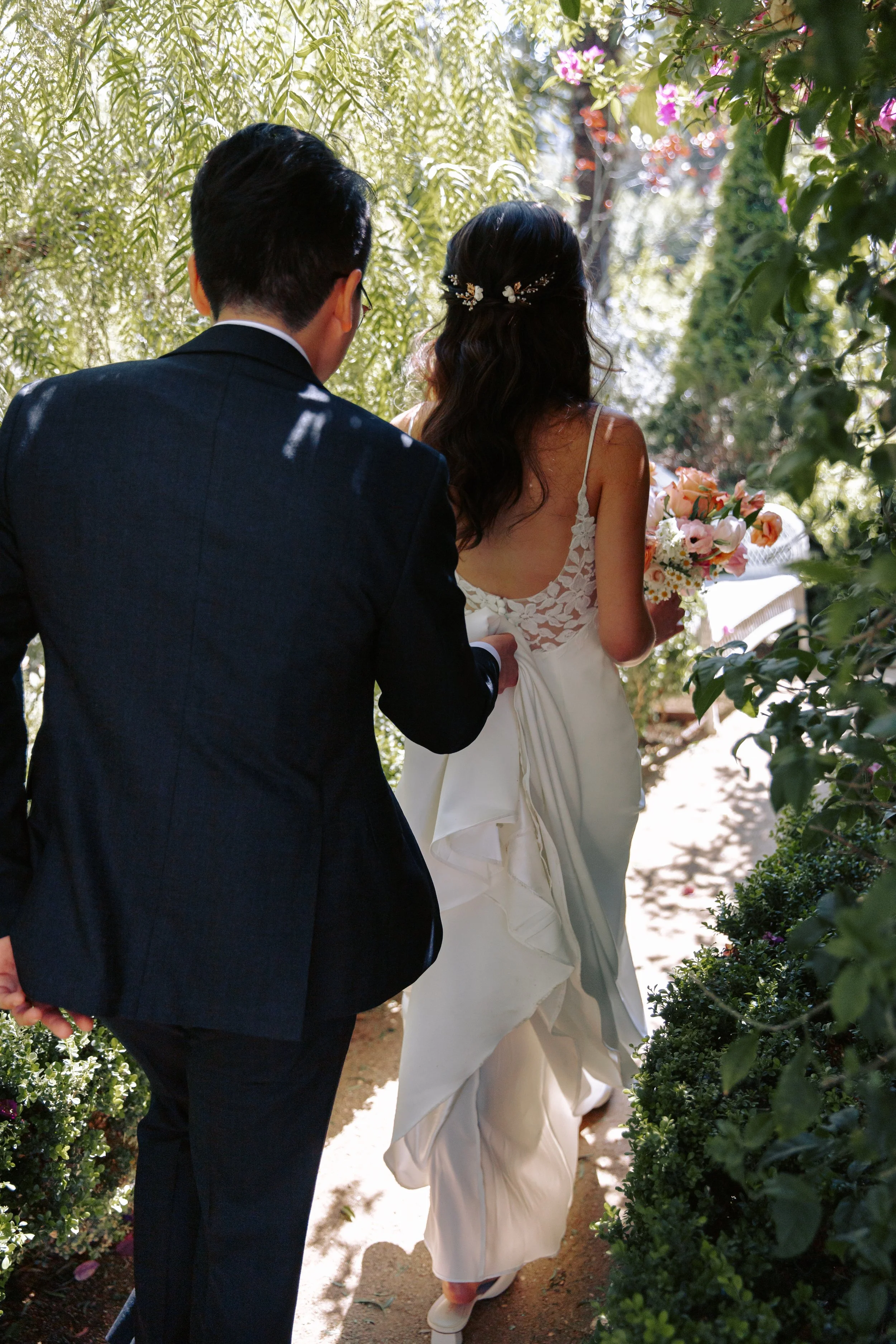Bride and groom walking through a garden pathway at XOHH Estate, a private wedding and event venue in the Hollywood Hills of Los Angeles.