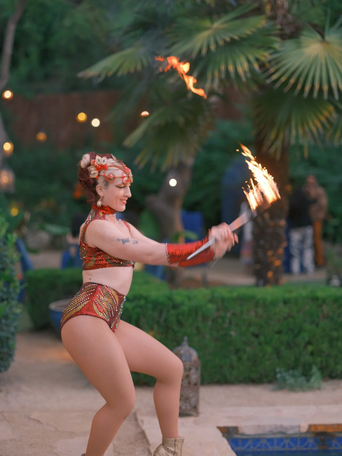 Fire dancer twirling a flaming baton in the garden at night