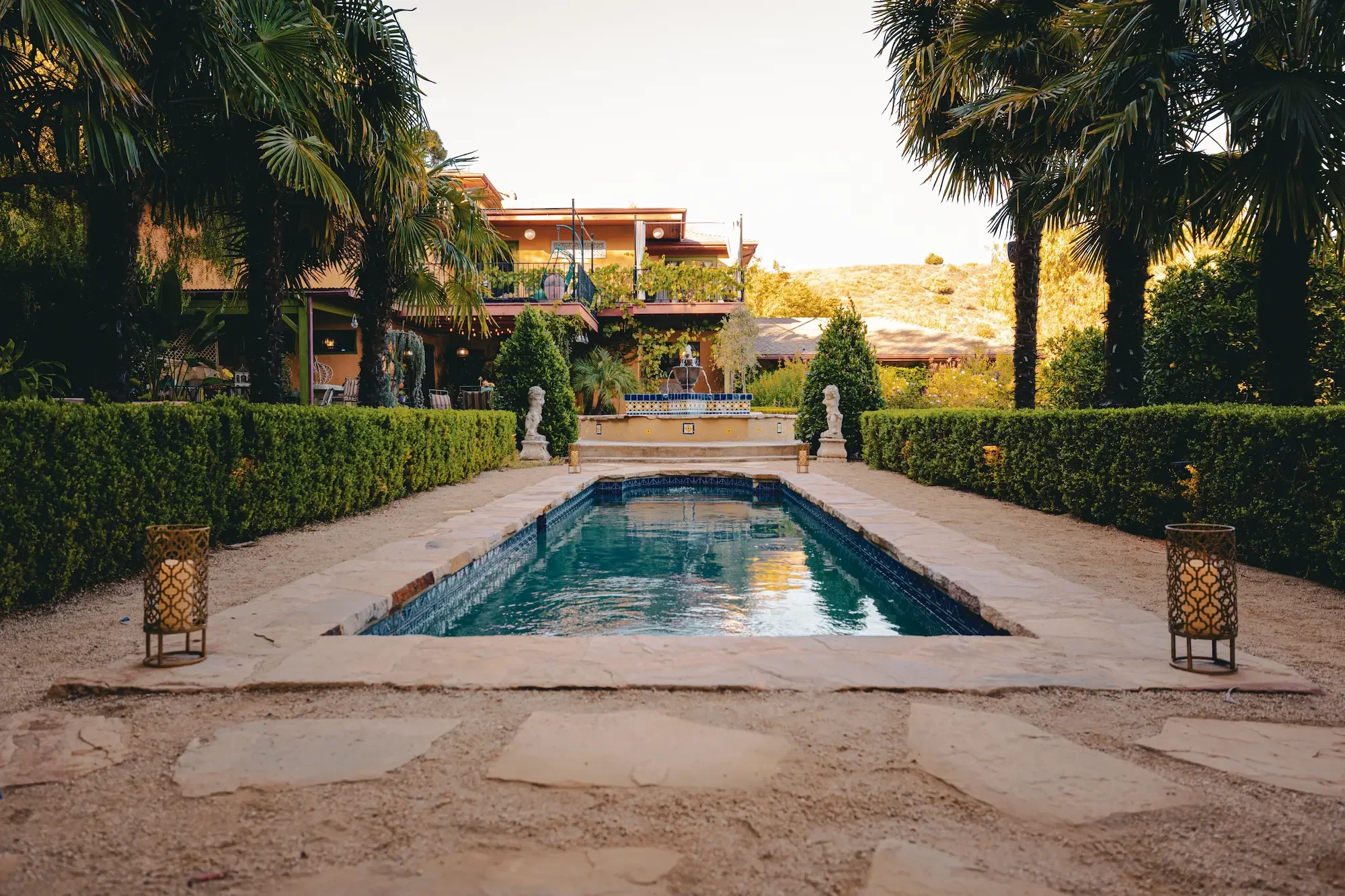 Wide view of the pool, landscaped gardens, estate residence, and surrounding Hollywood Hills.