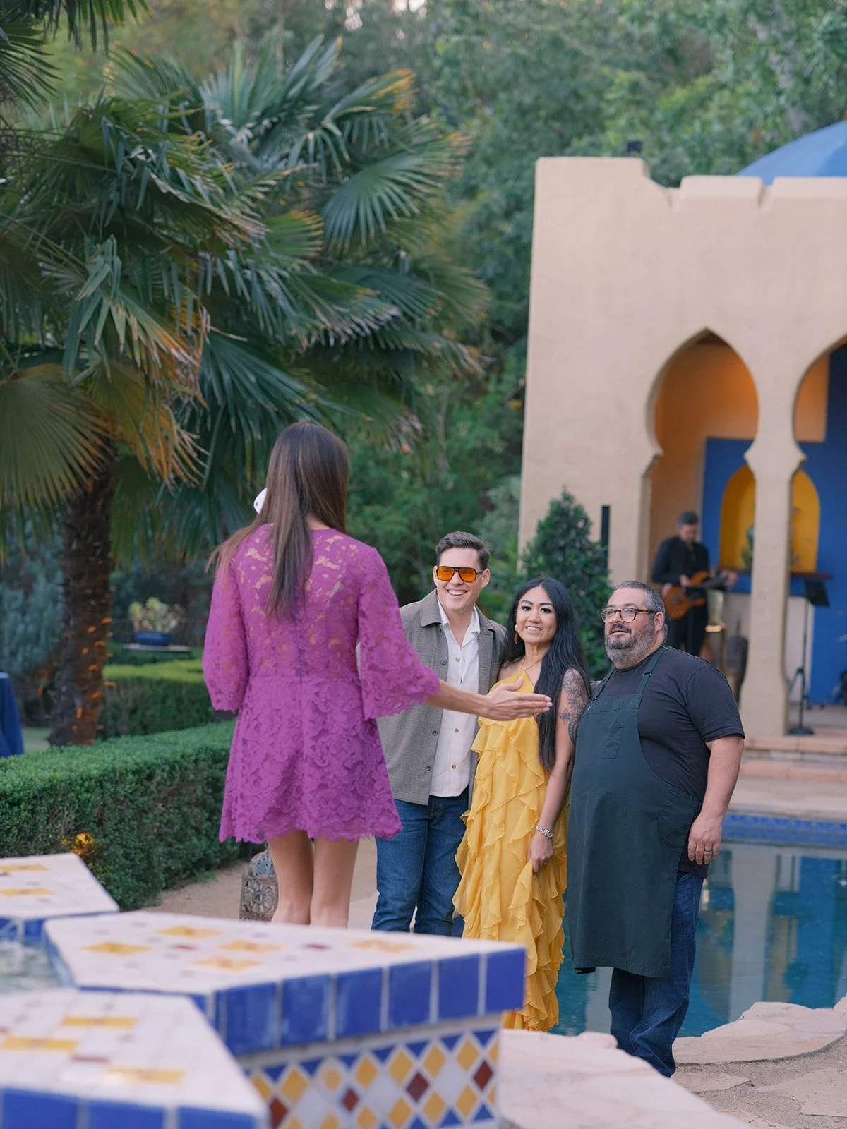 Hosts greeting guests by the pool beside the Moroccan pavilion