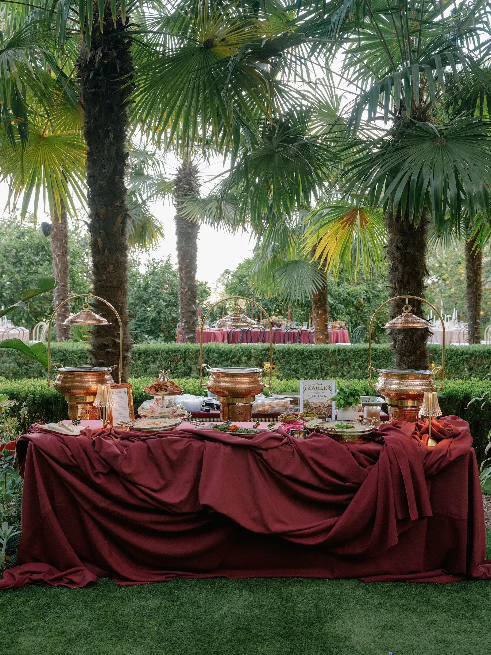 Outdoor dining setup surrounded by lush garden landscaping at XOHH Events.
