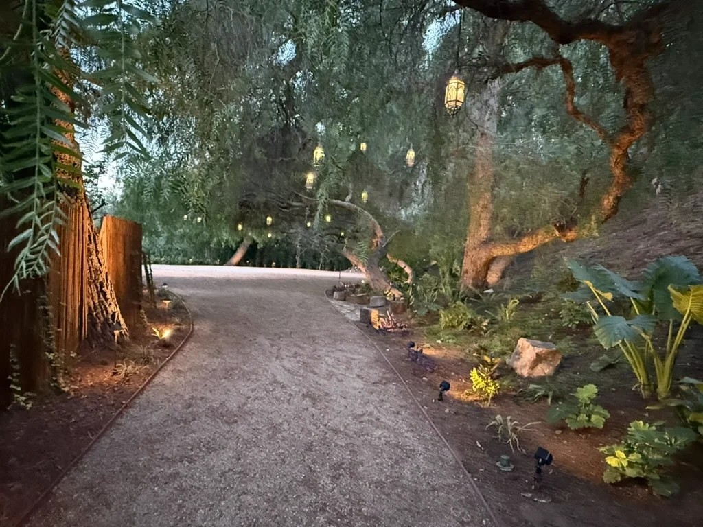 Lantern-lit garden pathway at dusk, hanging Moroccan lanterns glowing over a stone path