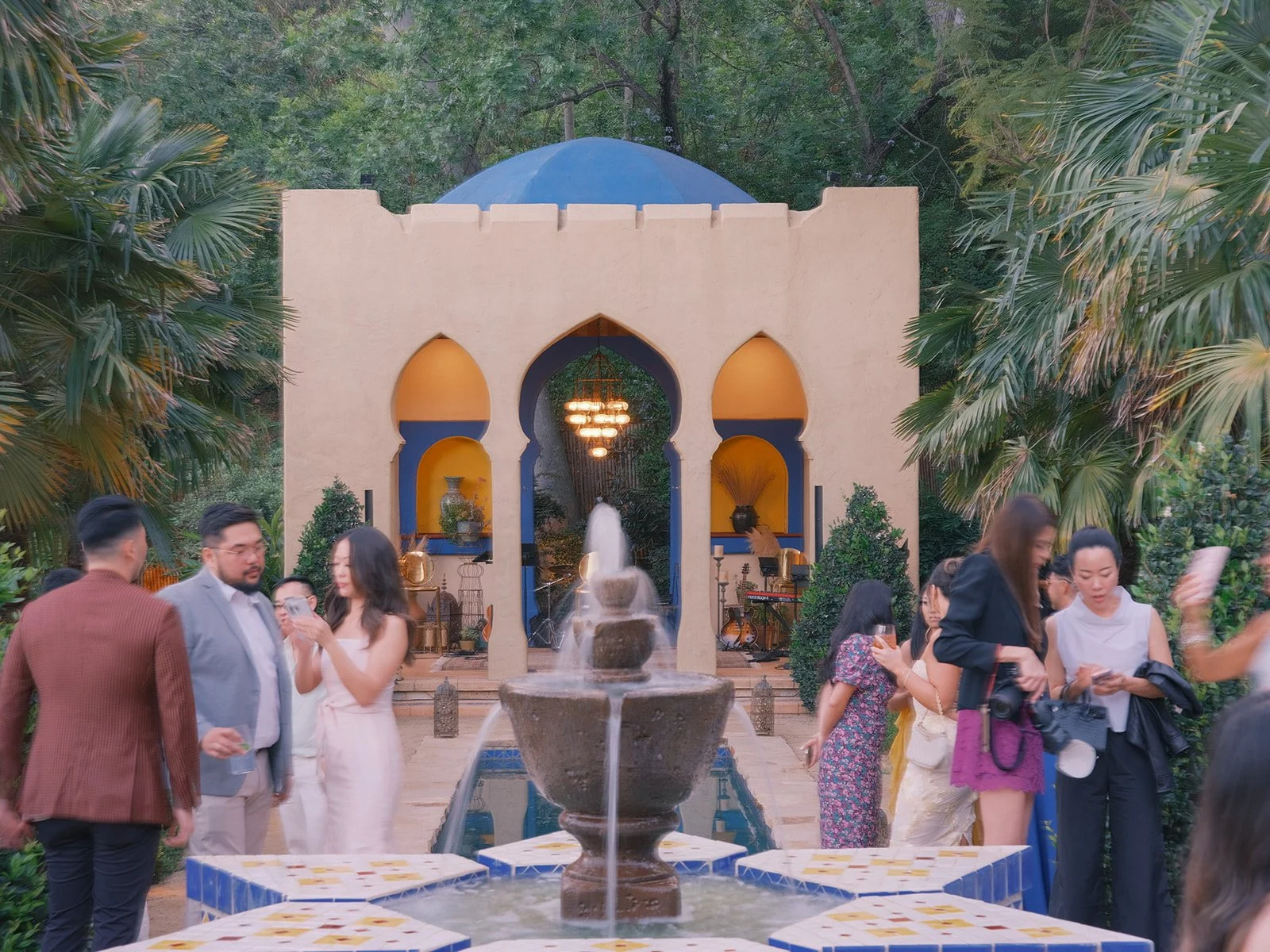 Guests mingling beside the Moroccan pavilion and fountain at a garden party