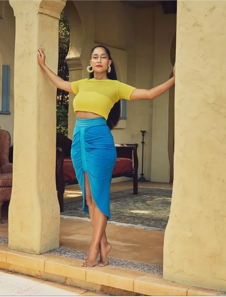 Editorial portrait in a yellow top and blue skirt against a Moroccan column