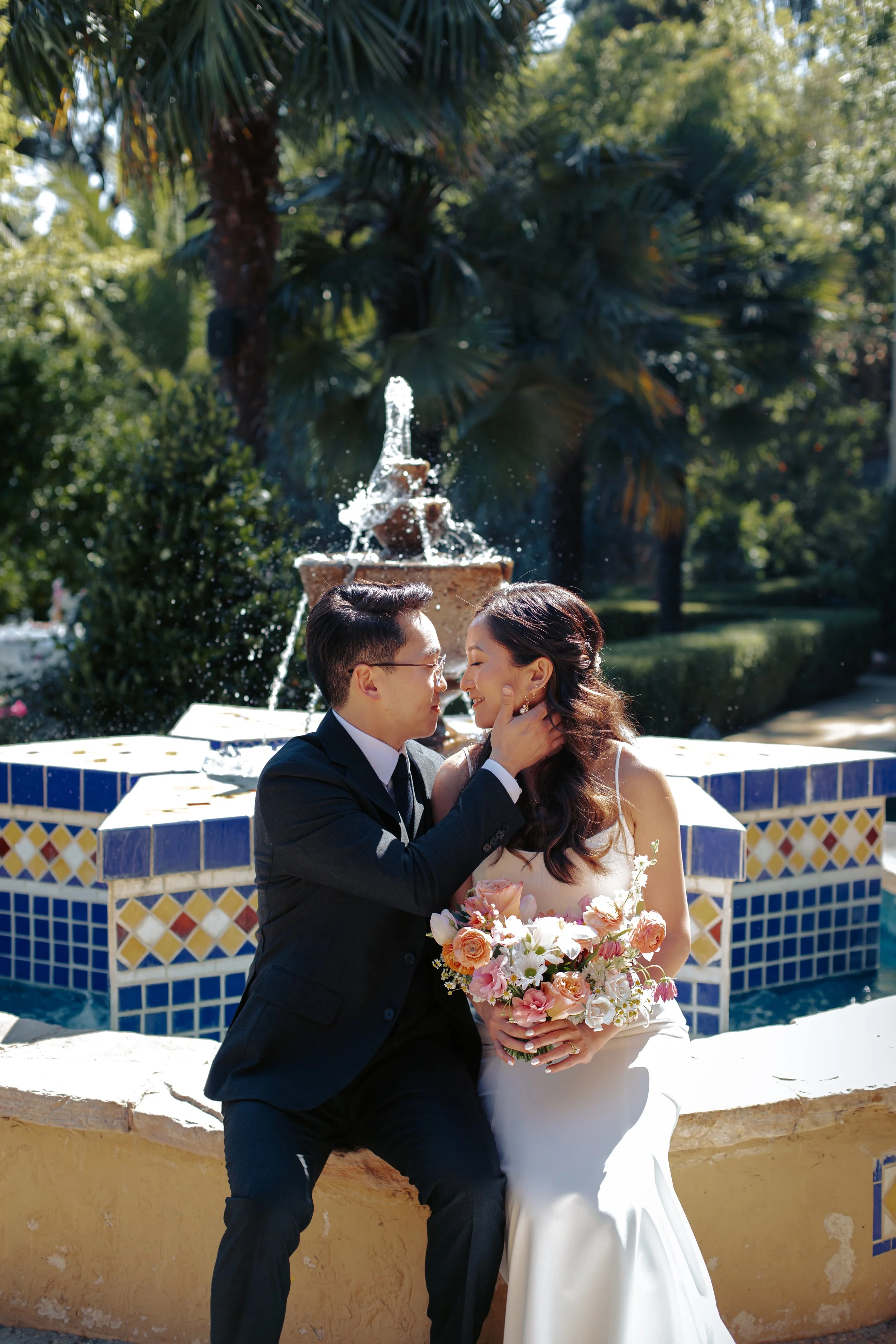 Newlyweds embracing beside the blue-tiled Moroccan fountain.
