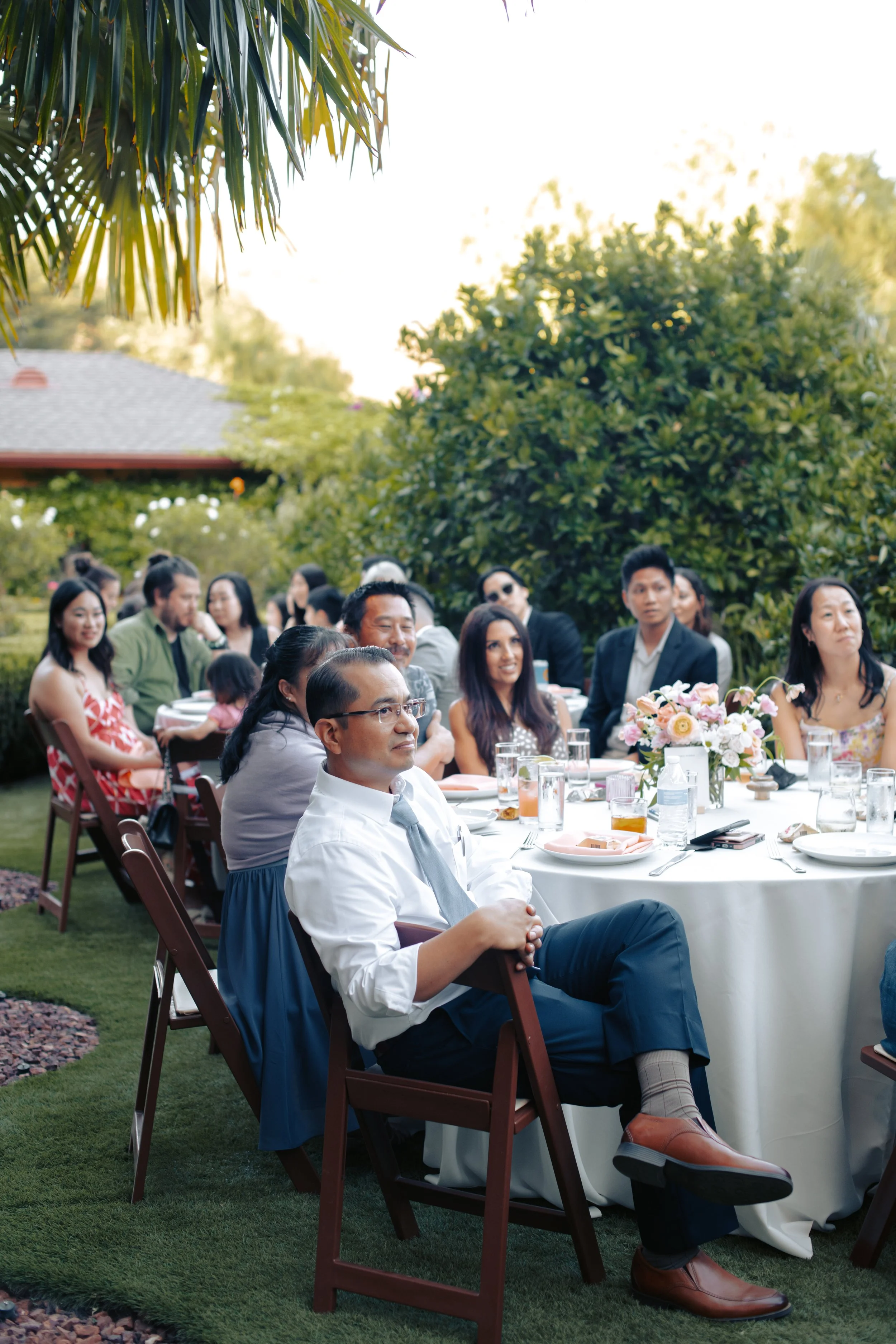 Guests seated at a long reception table under the garden canopy