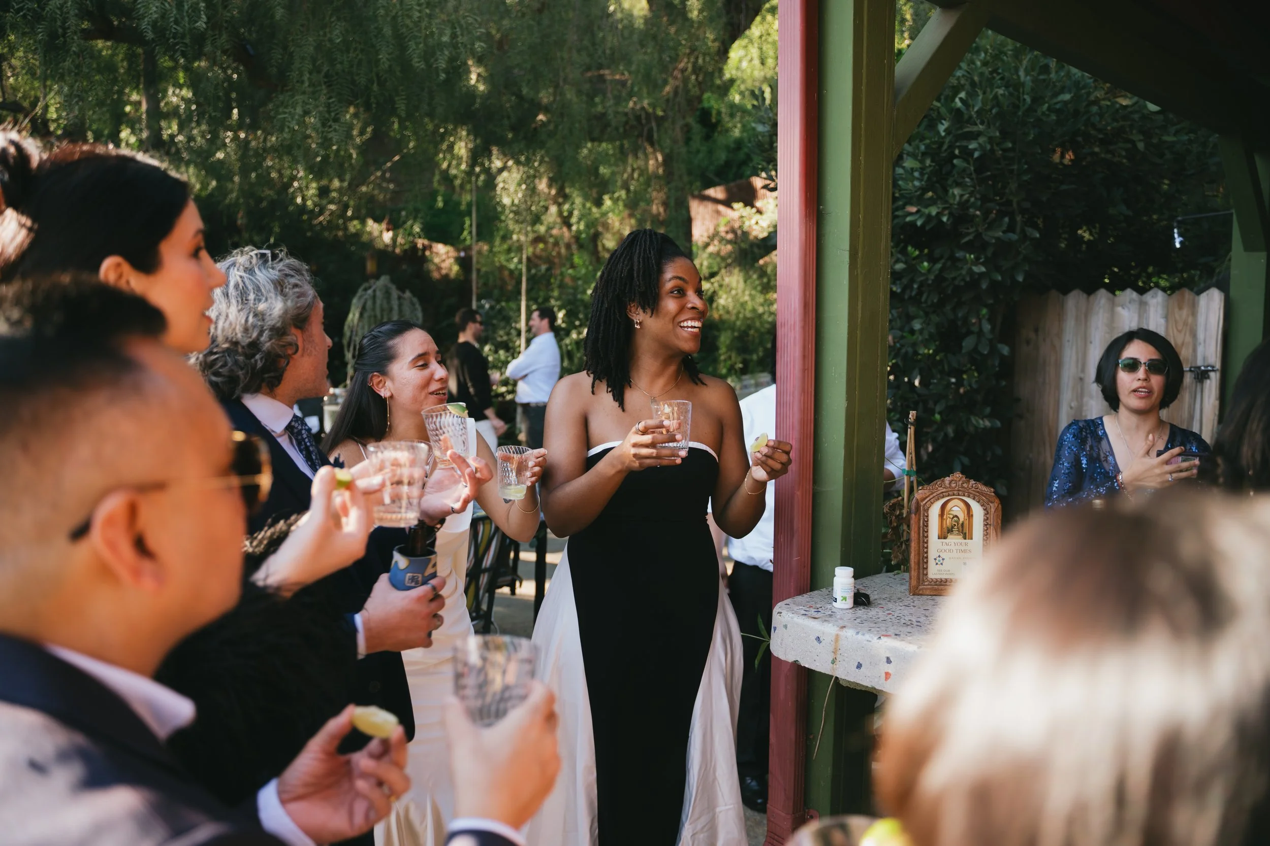 Guests toasting at cocktail hour, a woman in a black one-shoulder gown among them.