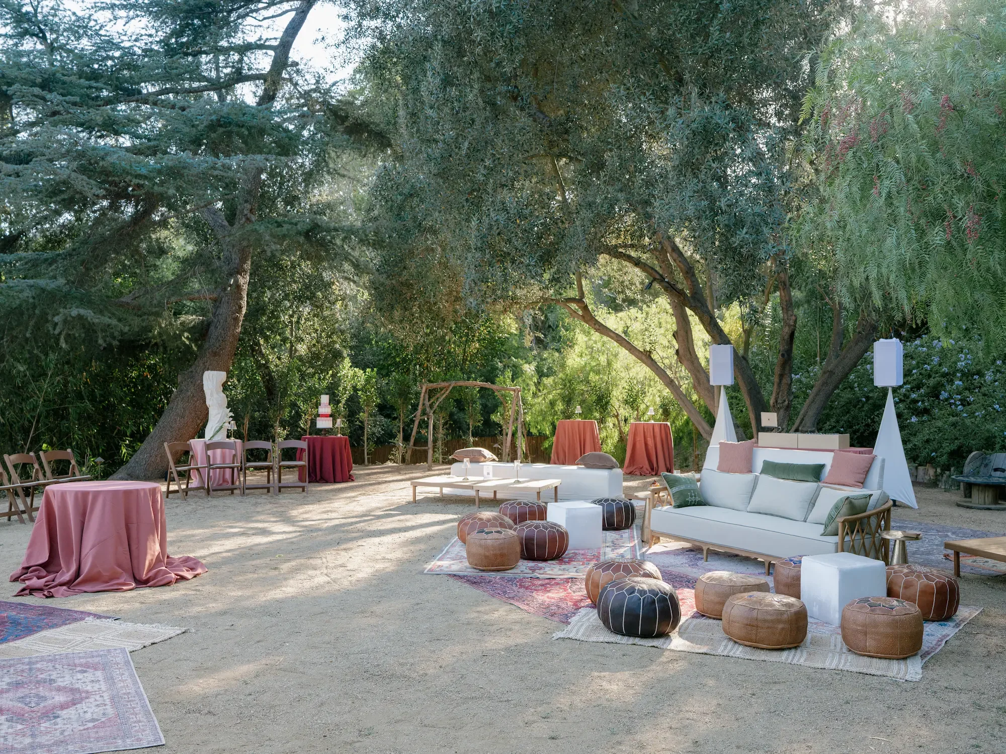 Moroccan lounge with leather poufs beneath a specimen olive tree and mature California pepper trees in Vista Grove.