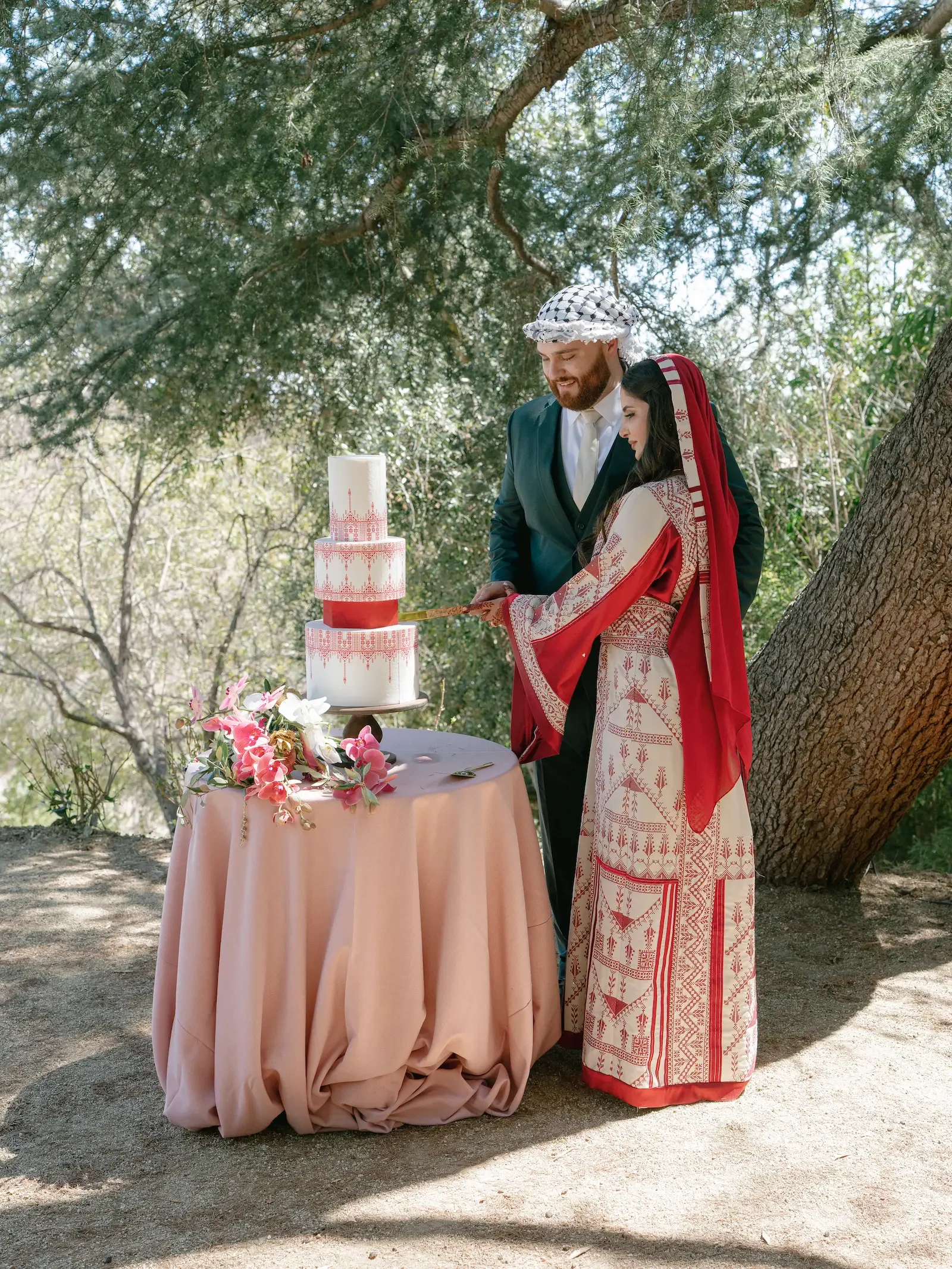 Middle Eastern bride and groom cutting their wedding cake beneath the garden trees at XOHH Events.