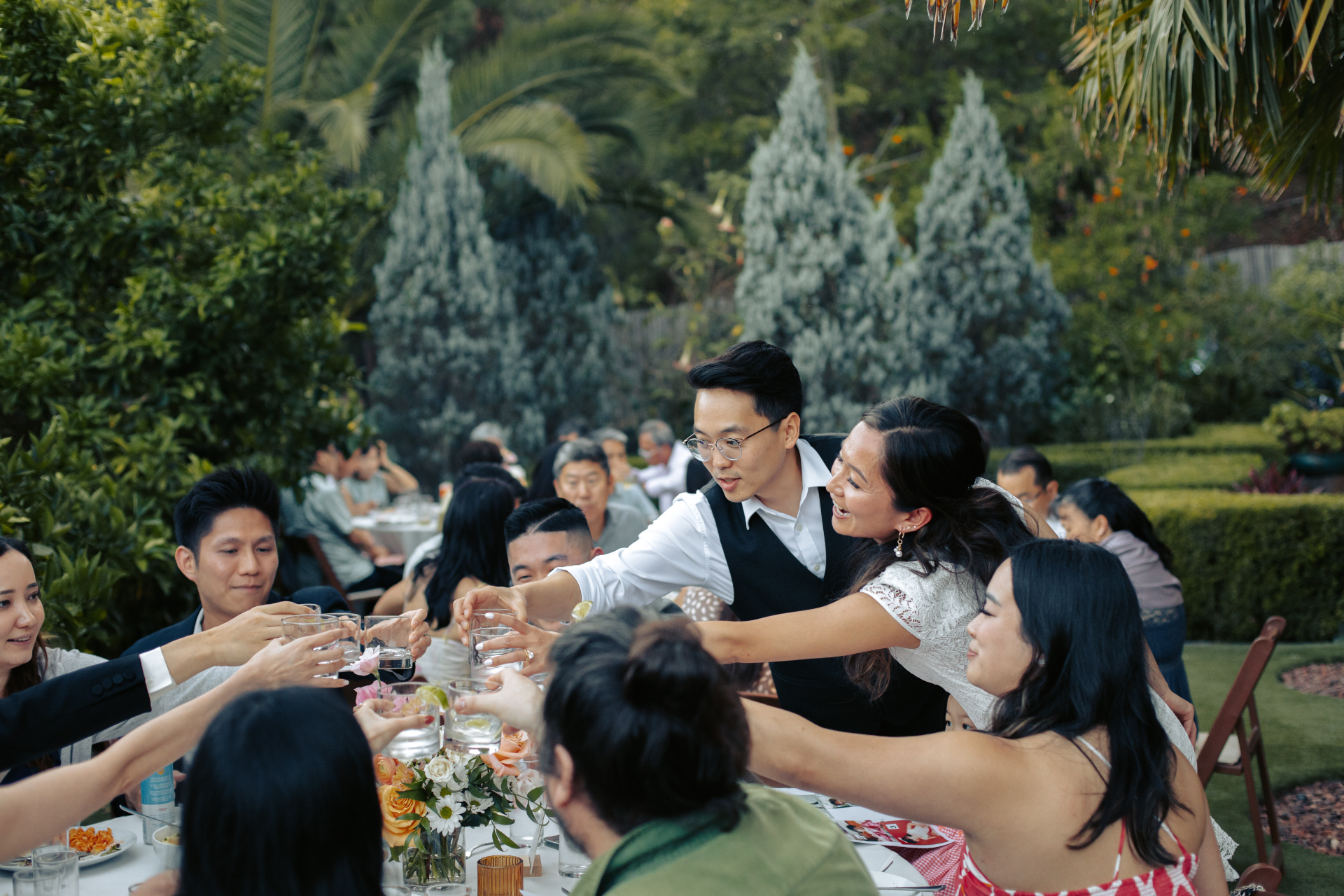 Wedding guests toasting and embracing at a candlelit reception table