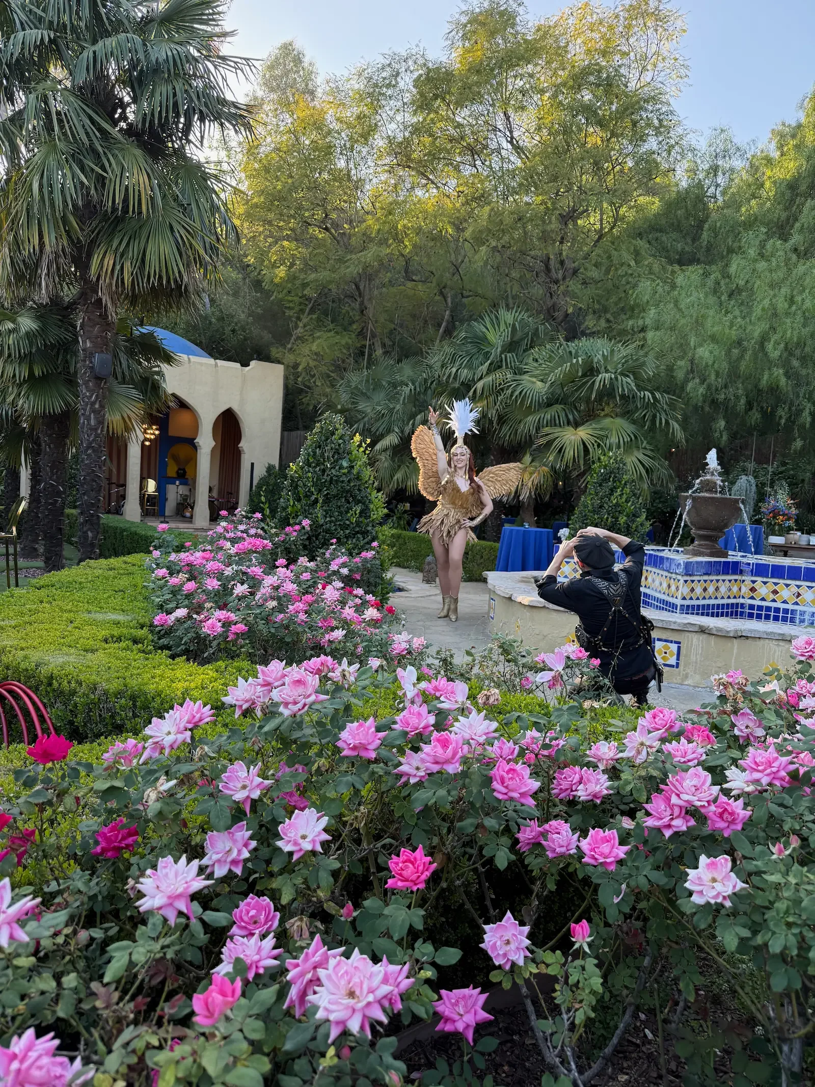 Performer posing for a photographer among the roses and fountain, with the Kasbah in the background at XOHH Events.