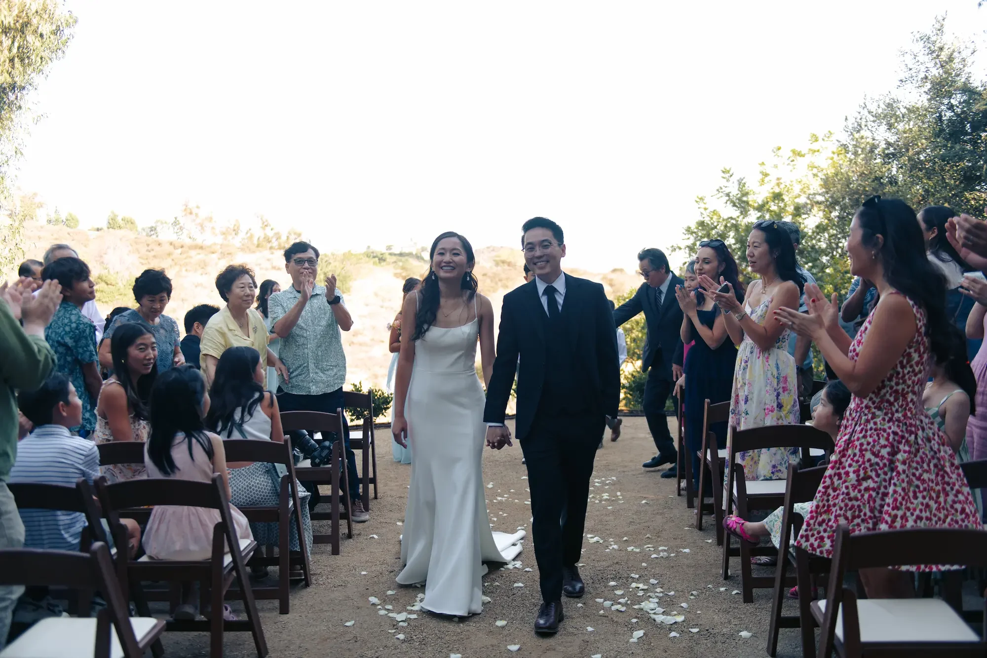 Newlyweds walking together after their ceremony as guests celebrate at XOHH Events.