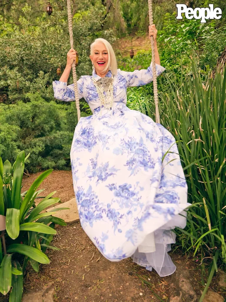 Model in a blue-and-white floral gown on a garden swing among the greenery